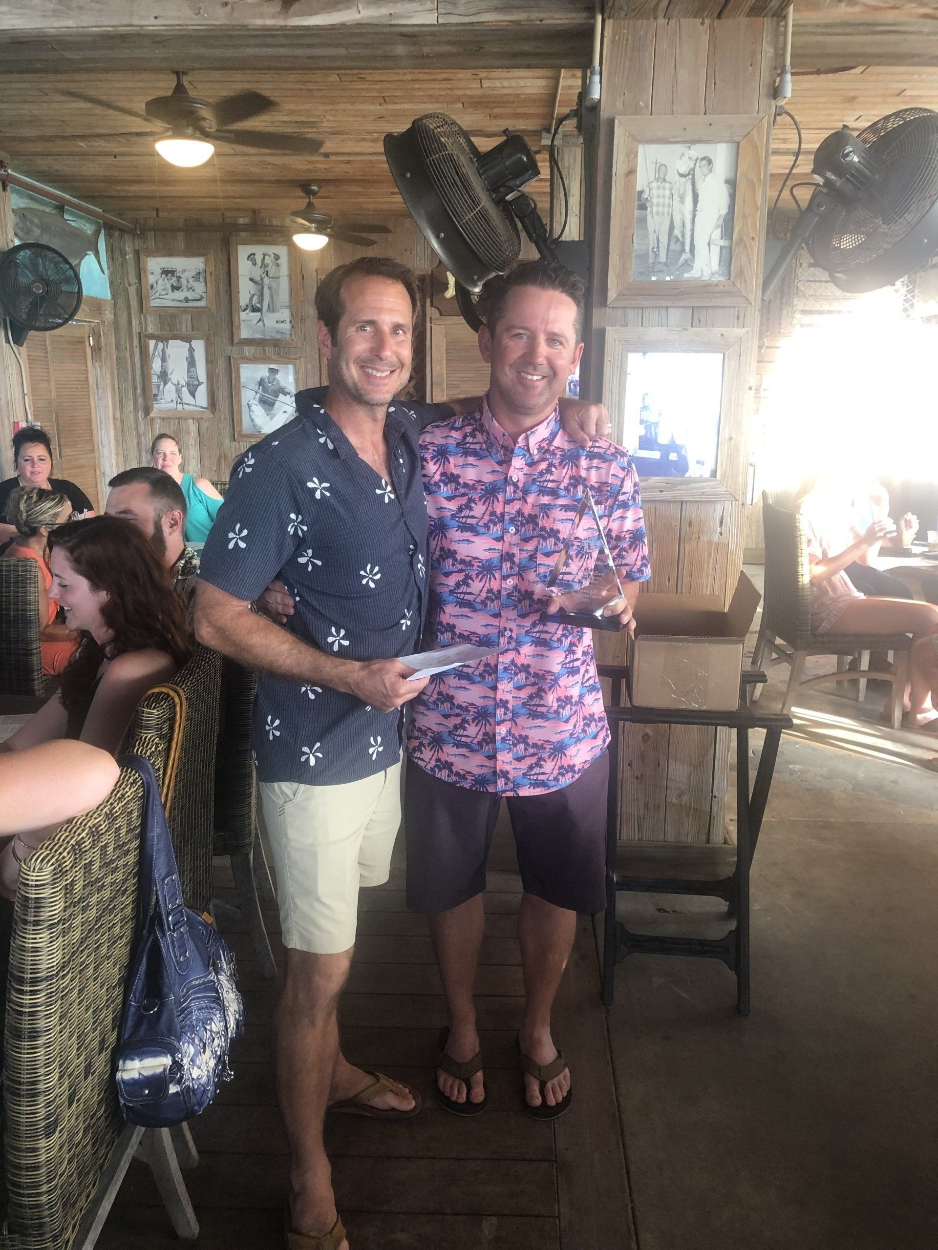Two men are standing next to each other in a restaurant.