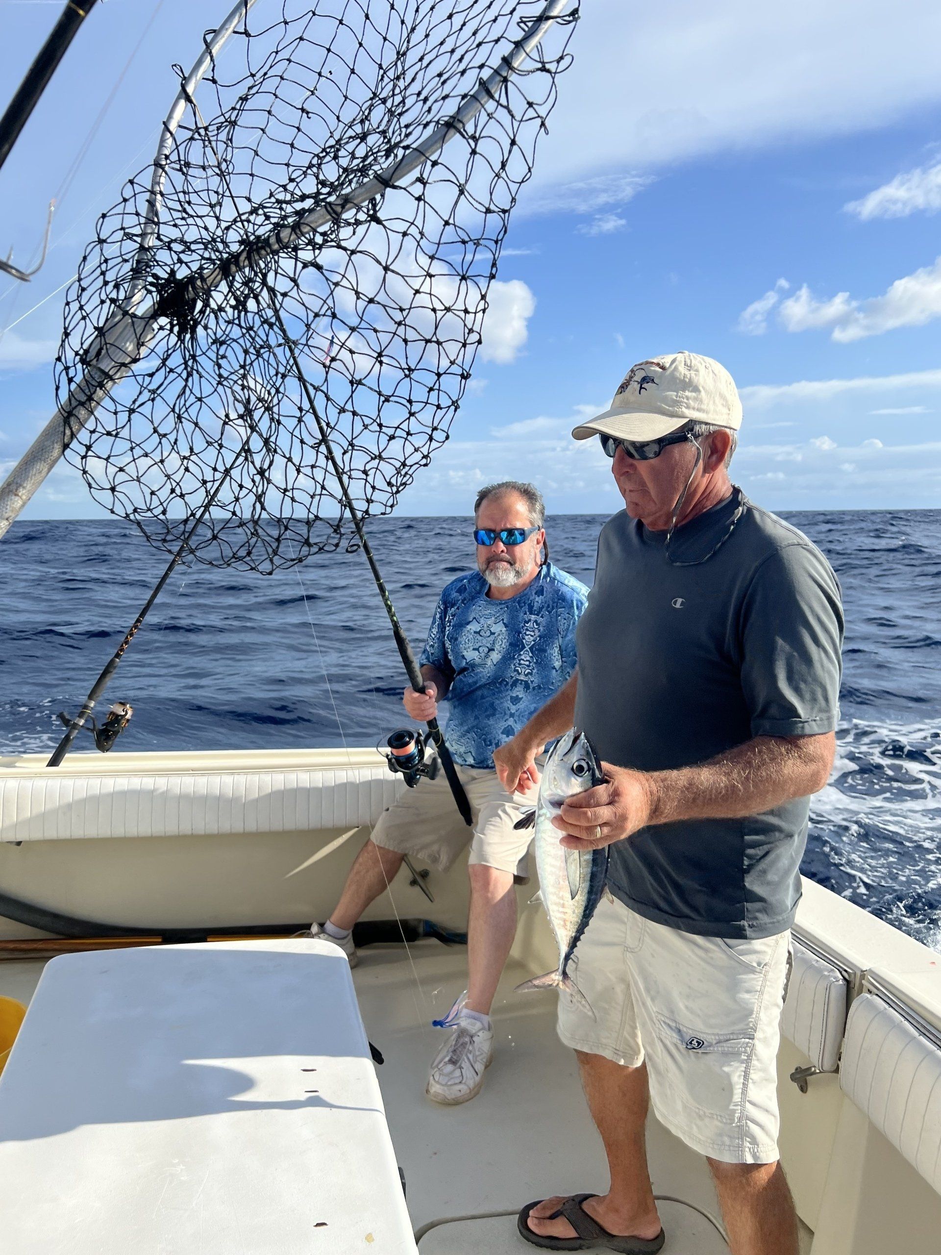 Two men are fishing on a boat in the ocean.