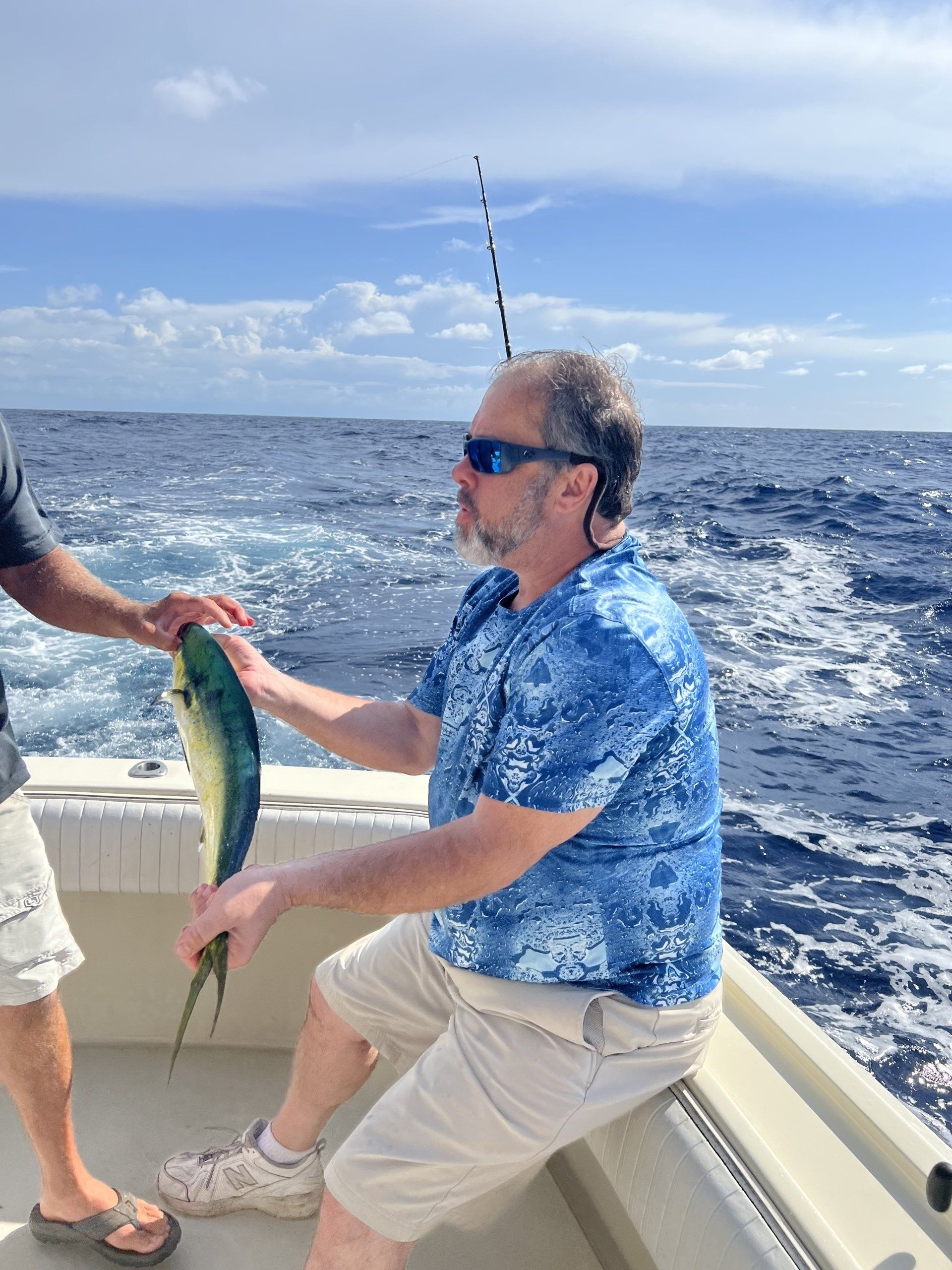 A man is holding a fish on a boat in the ocean