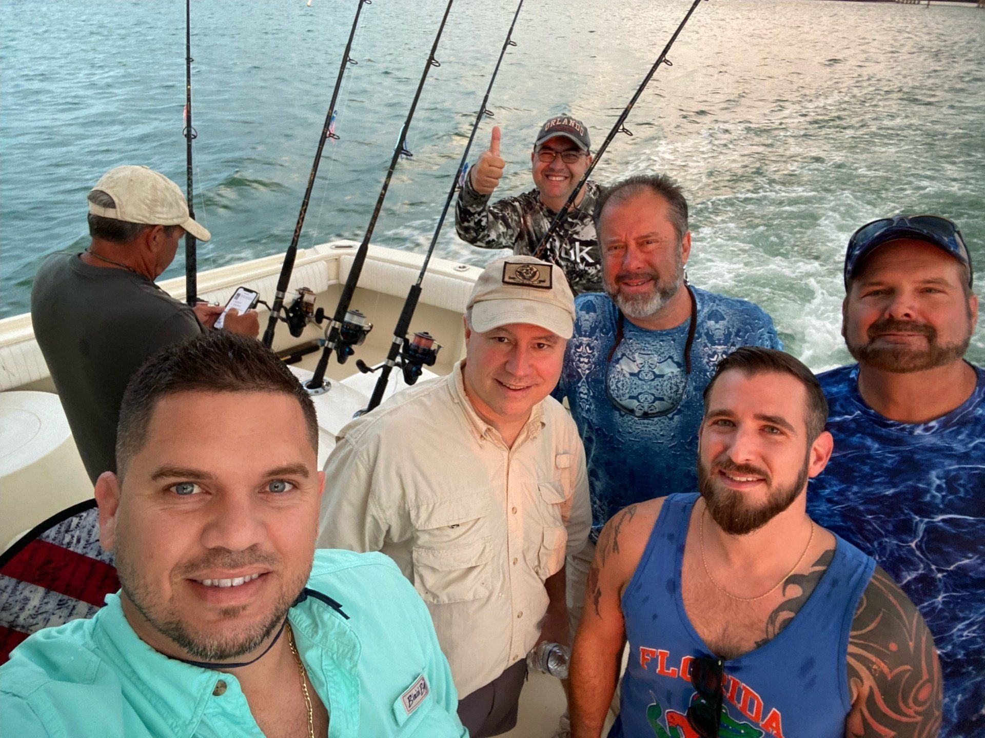 A group of men are standing on a boat with fishing rods.