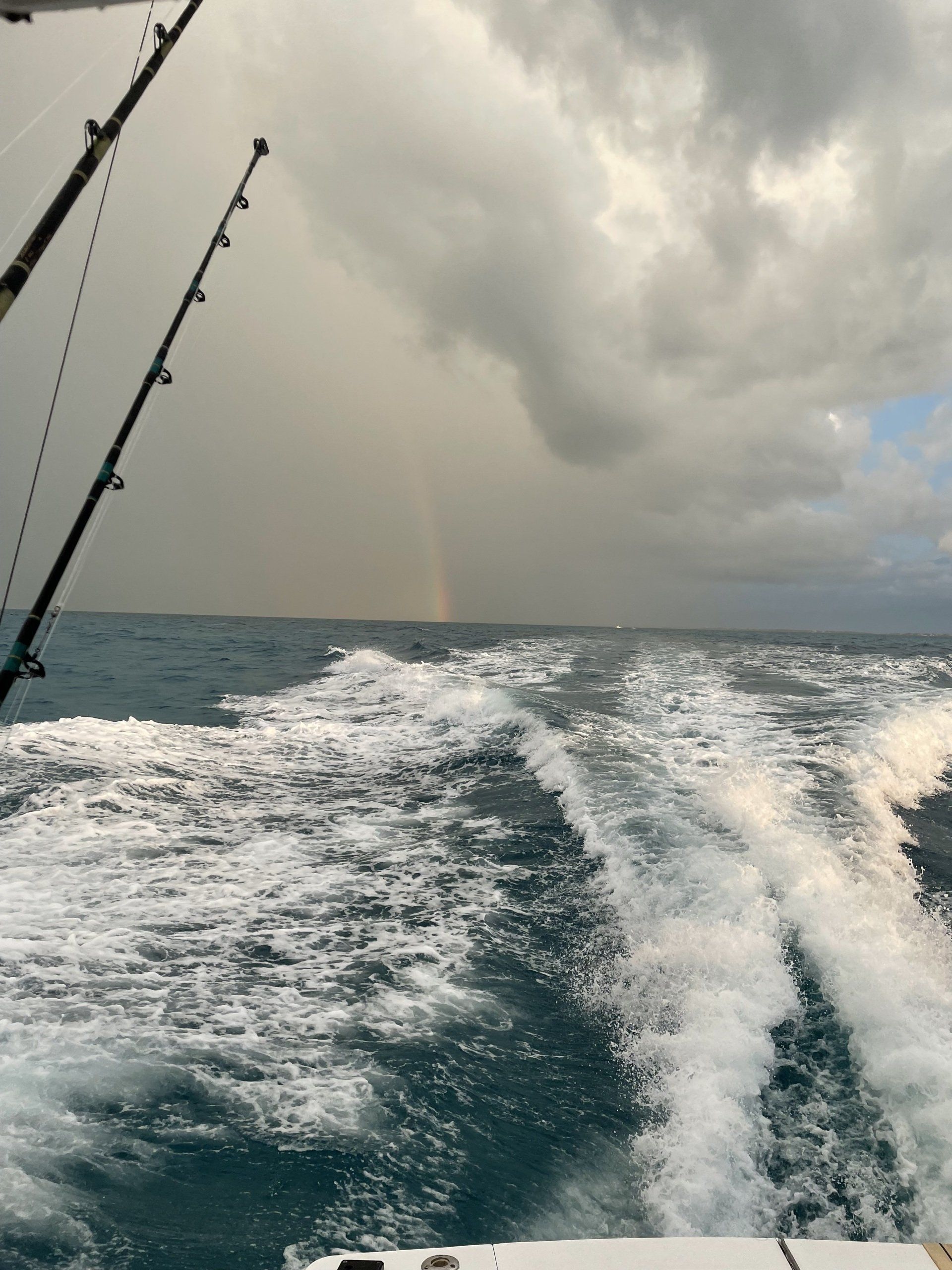 A boat in the ocean with a rainbow in the distance