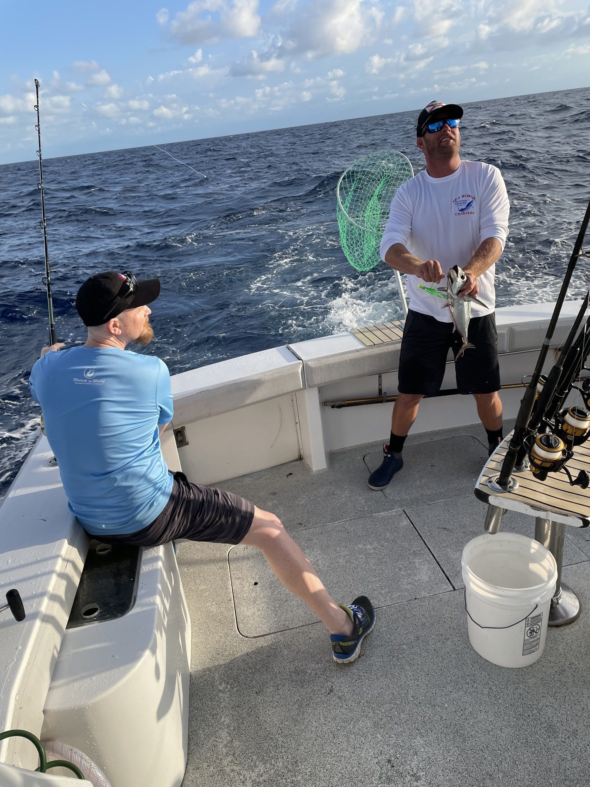 Two men are fishing on a boat in the ocean.