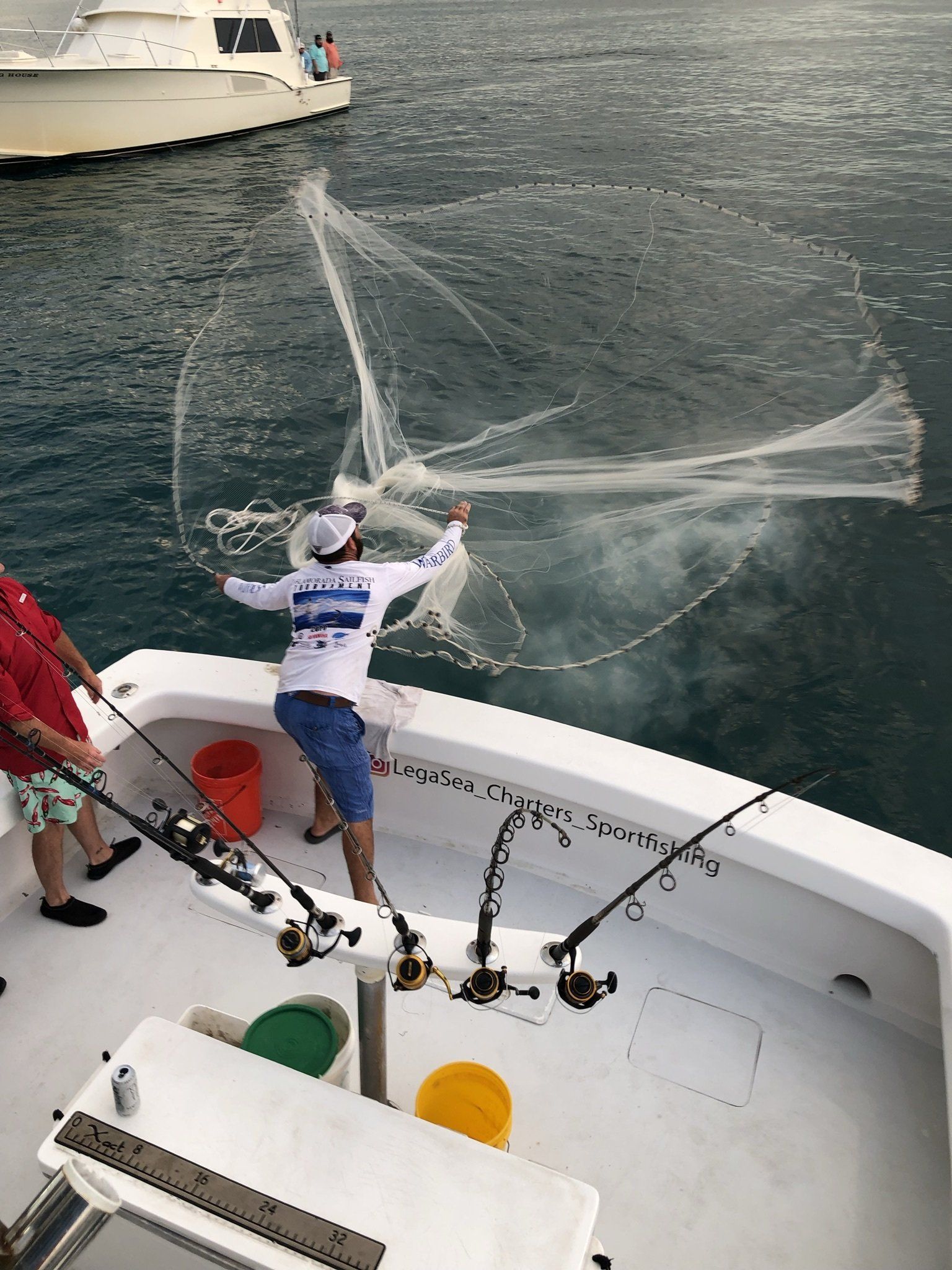 A man is fishing with a net on a boat.