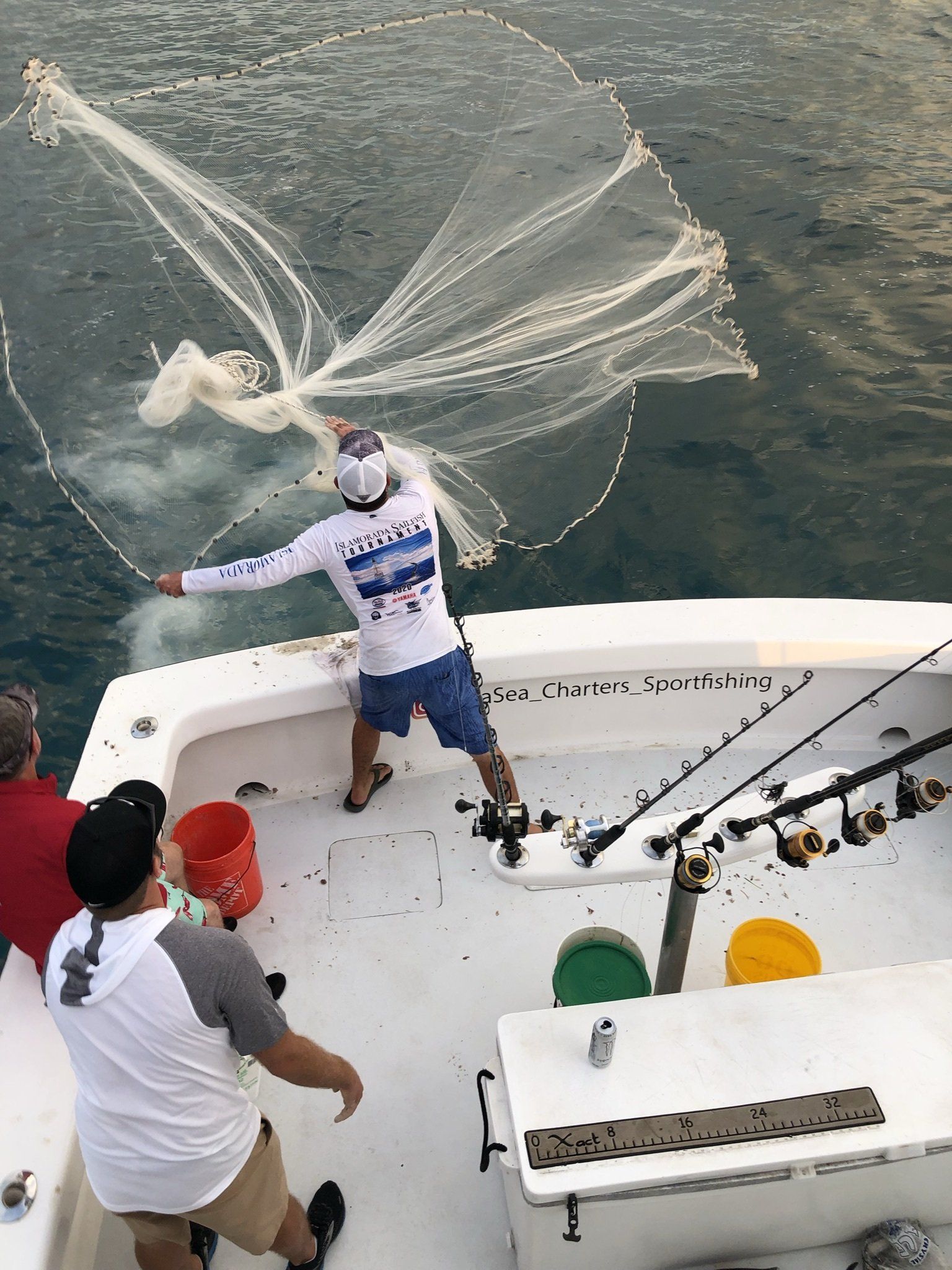 A man is throwing a net in the water on a boat.