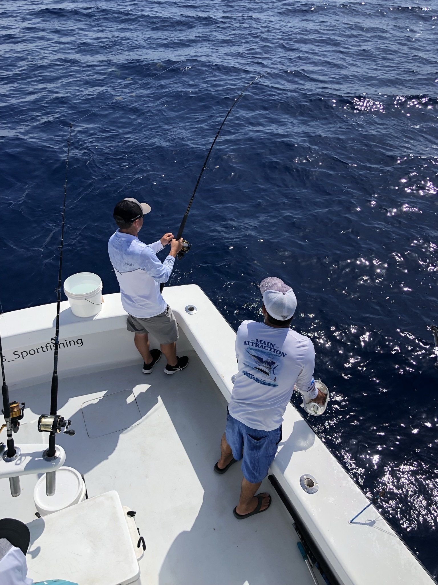 Two men are fishing on a boat in the ocean.