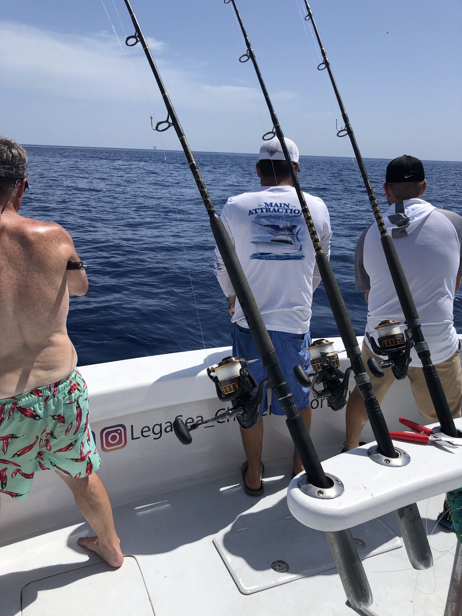 Three men are fishing on a boat in the ocean.