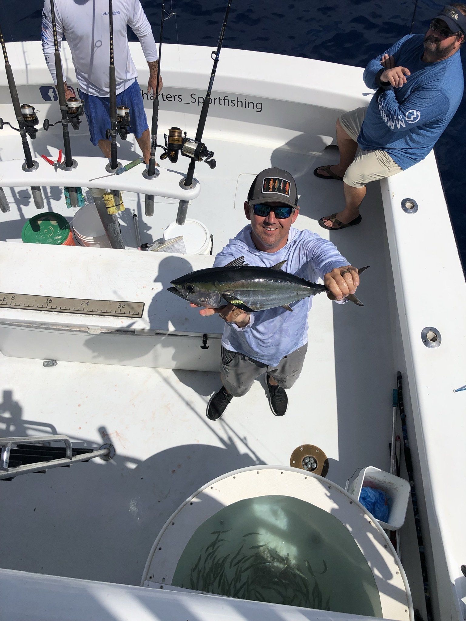 A man is holding a fish on the deck of a boat.