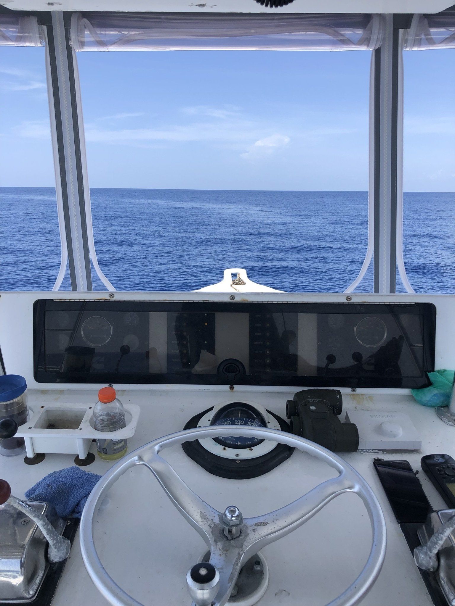 A steering wheel on a boat with a view of the ocean.
