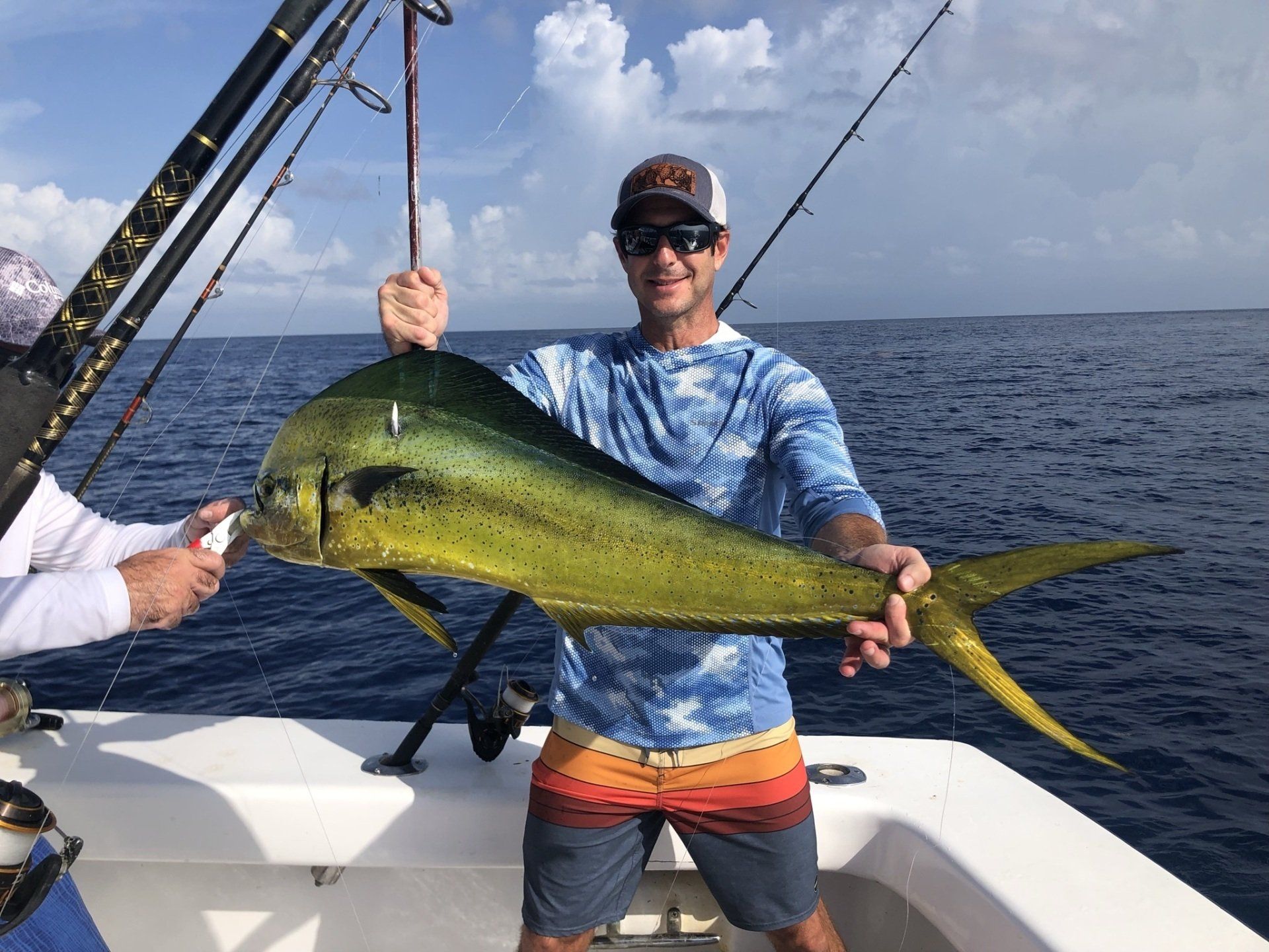 A man is holding a large fish on a boat in the ocean.