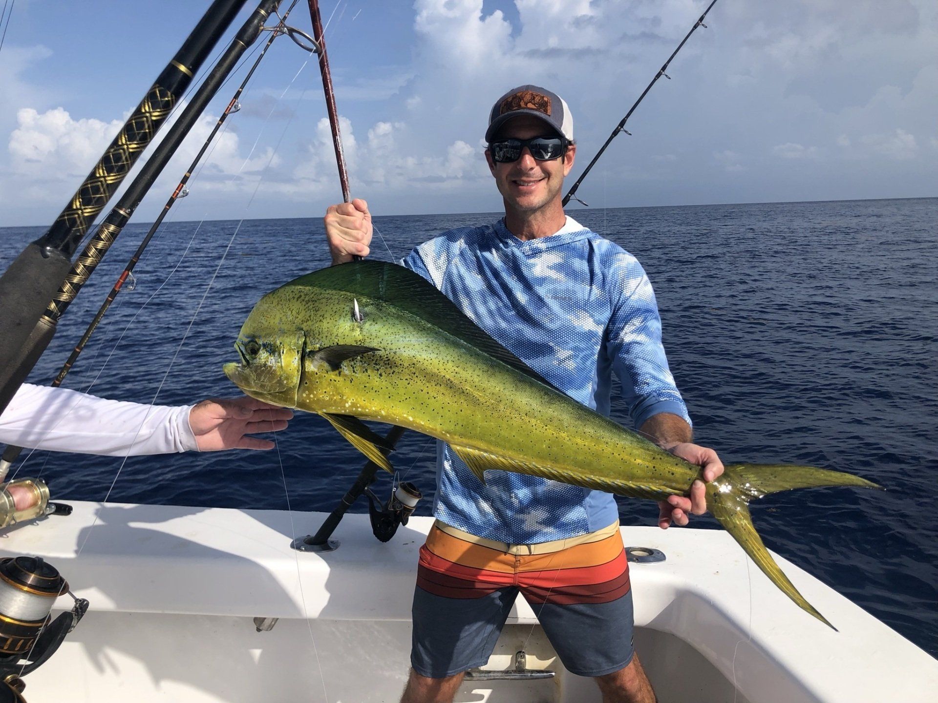 A man is holding a large fish on a boat in the ocean.