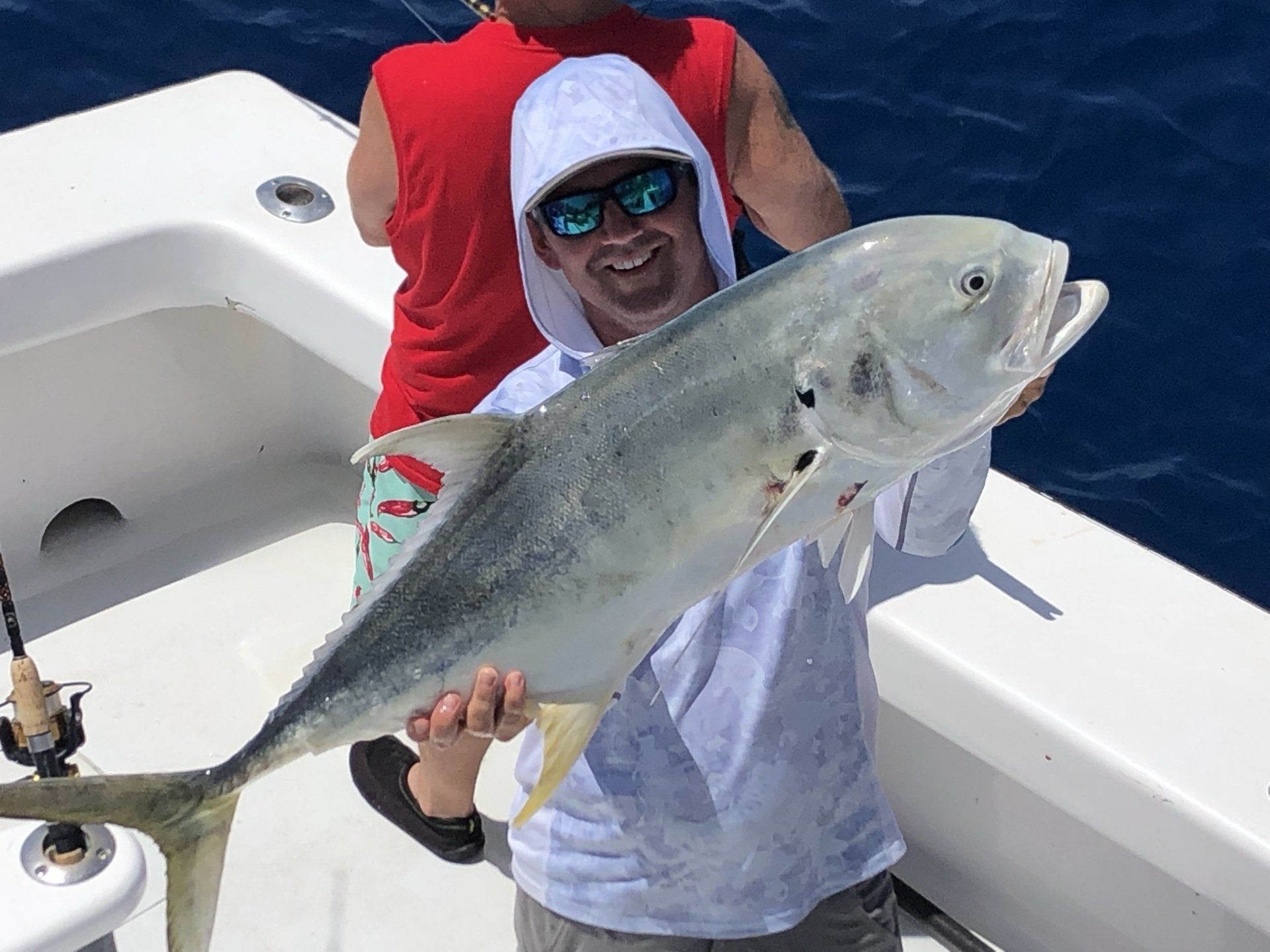 A man is holding a large fish on a boat.