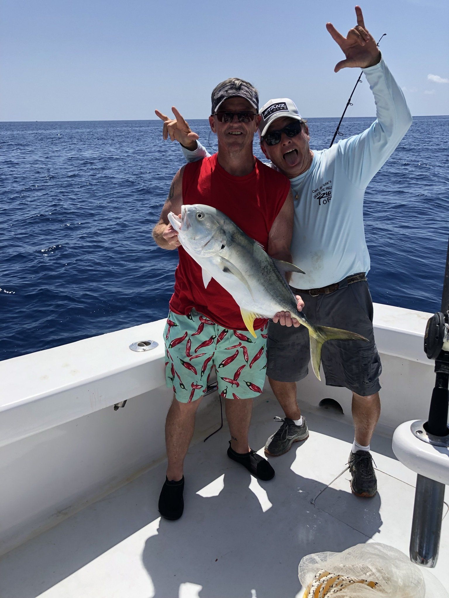 Two men are standing on a boat holding a fish.