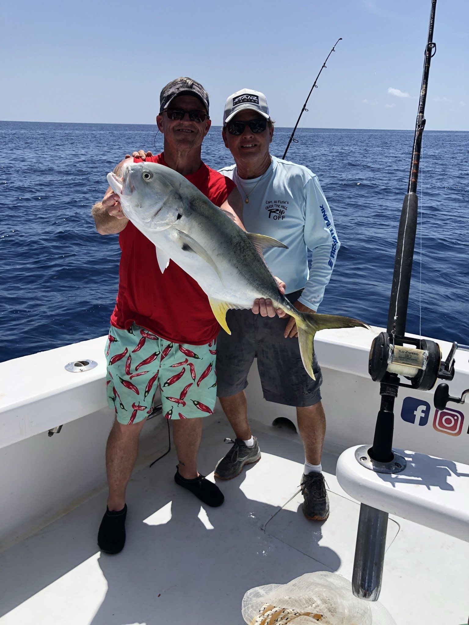 Two men are standing on a boat holding a fish.