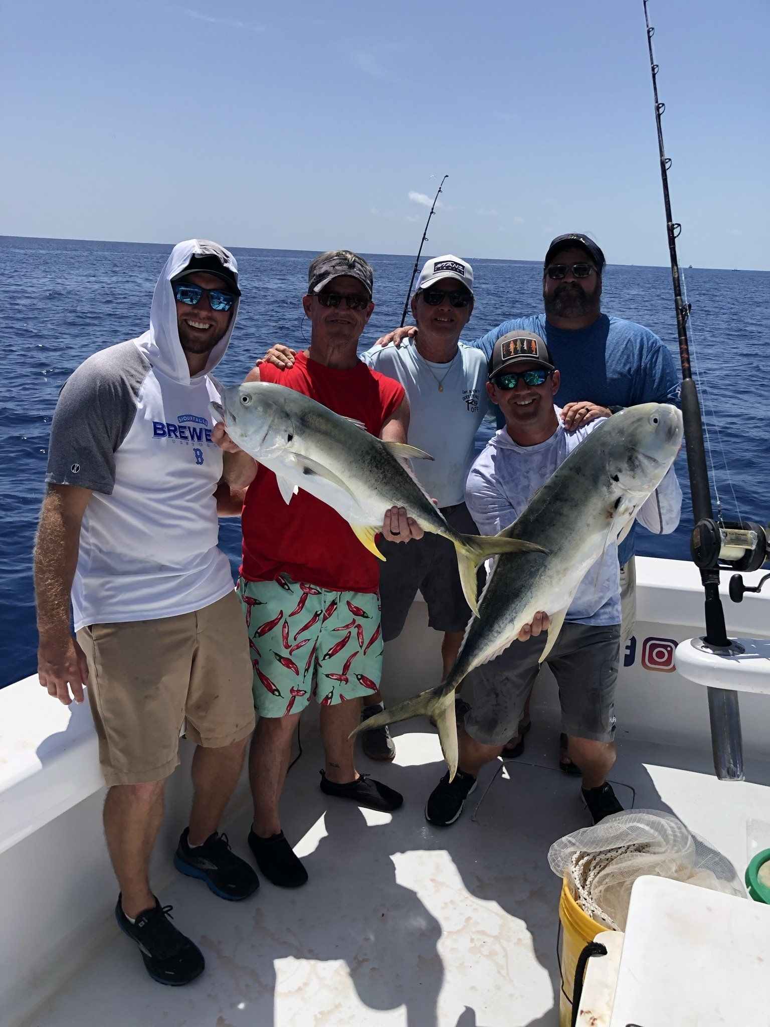 A group of men are standing on a boat holding fish.