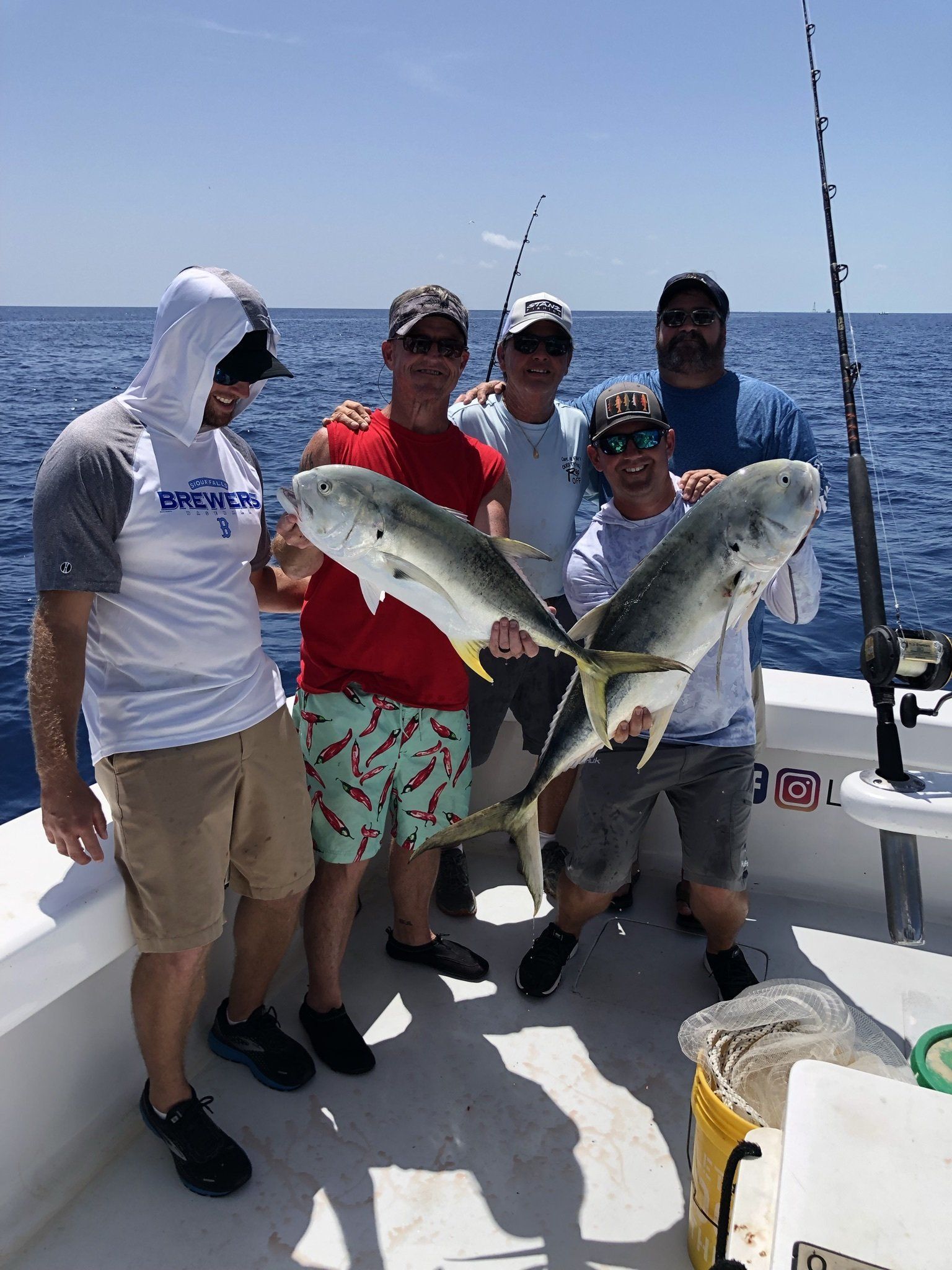 A group of men are standing on a boat holding fish.