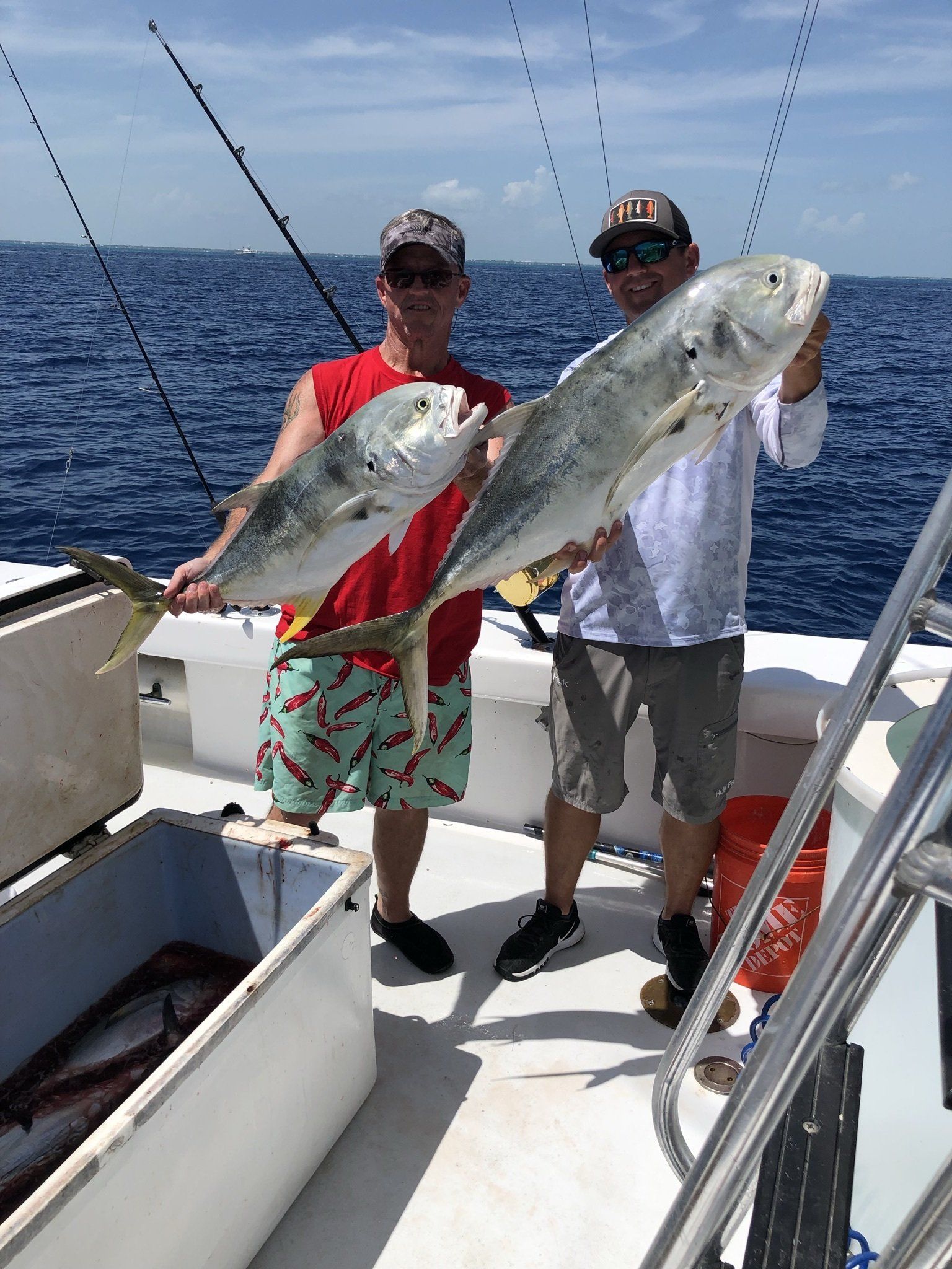 Two men are standing on a boat holding two fish.