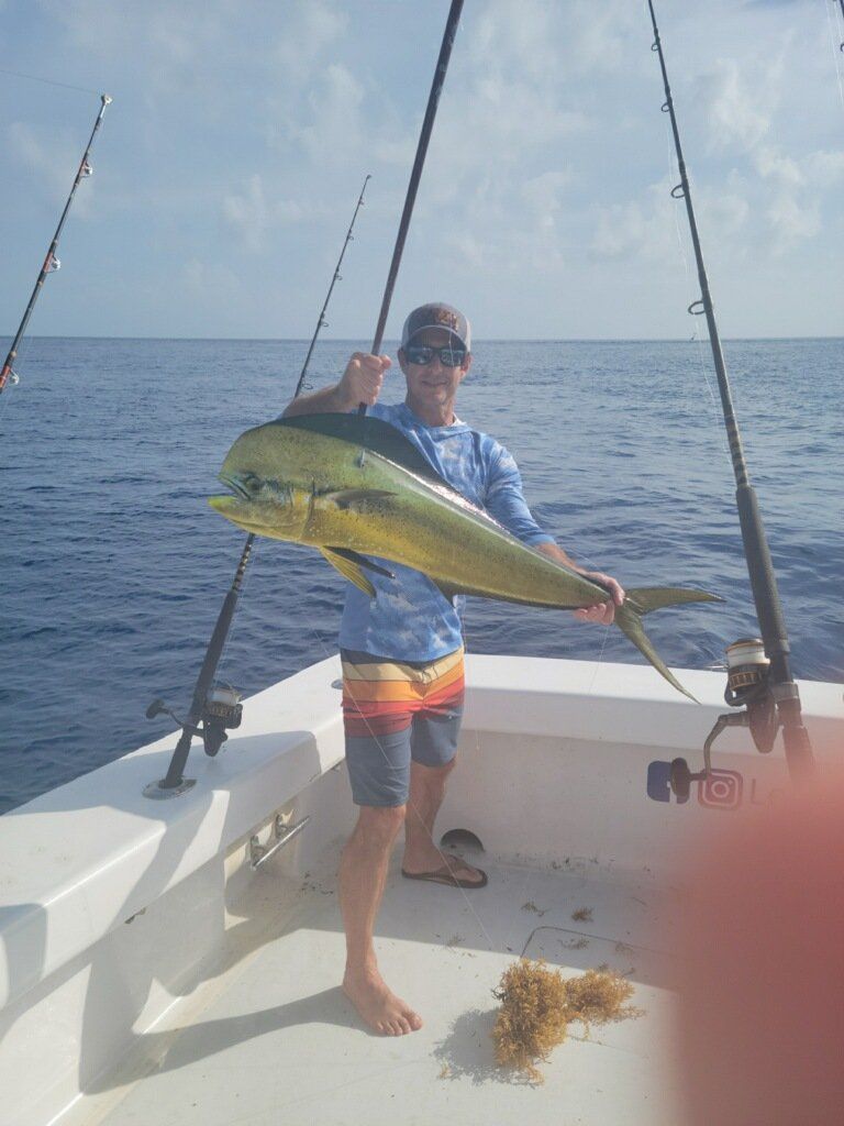 A man is standing on a boat holding a large fish.