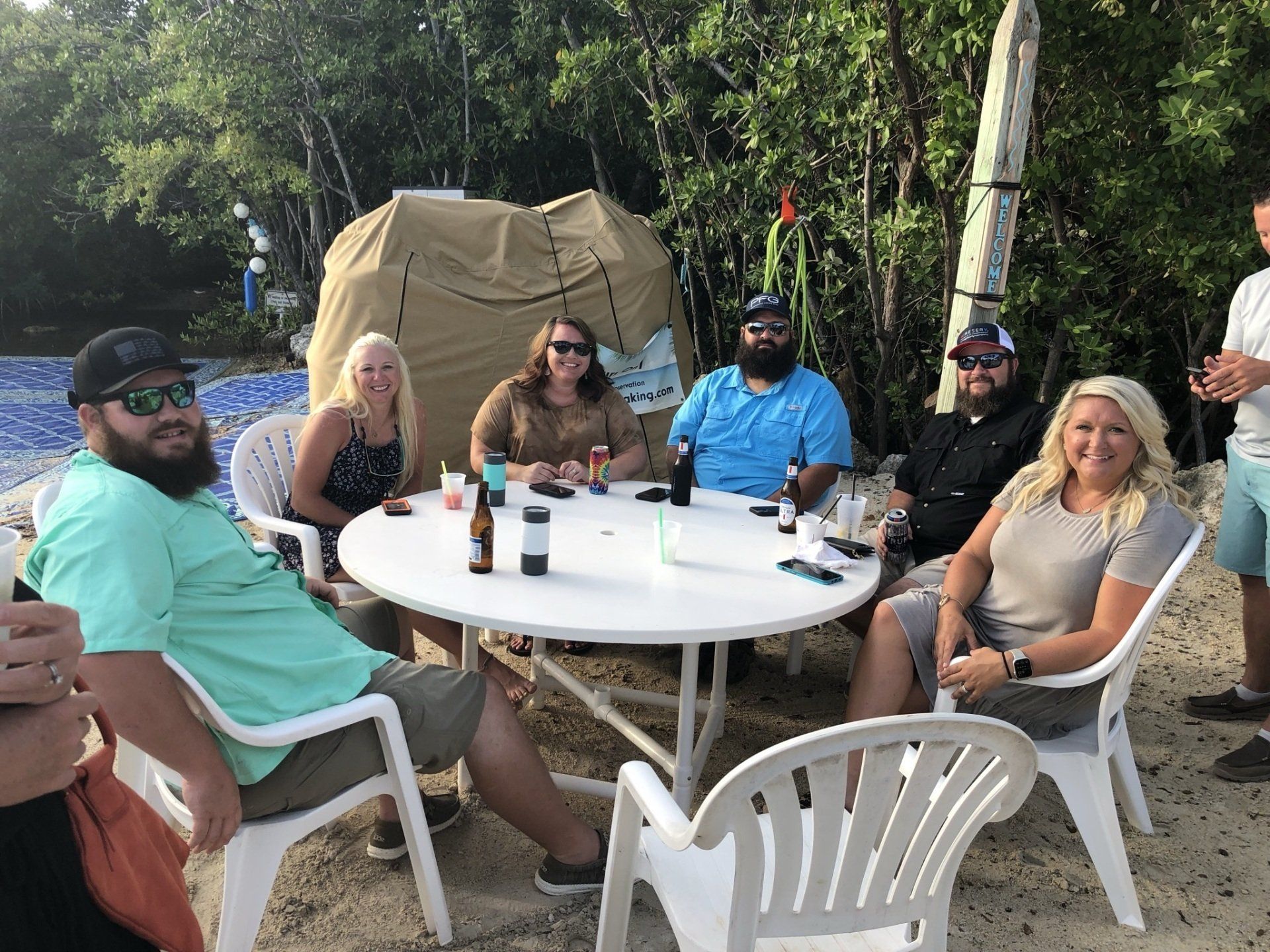 A group of people are sitting around a table on the beach.