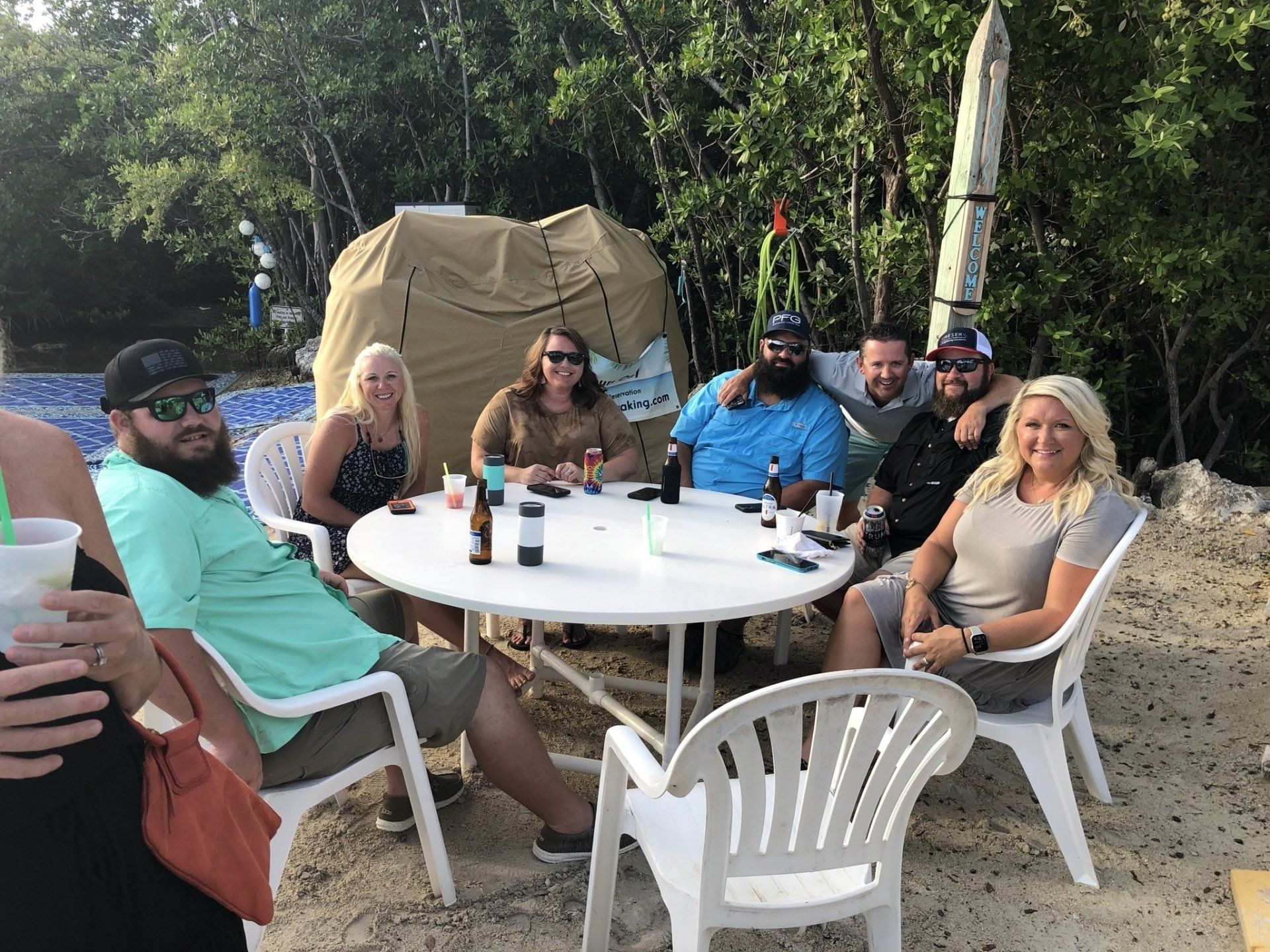 A group of people are sitting around a table on the beach.