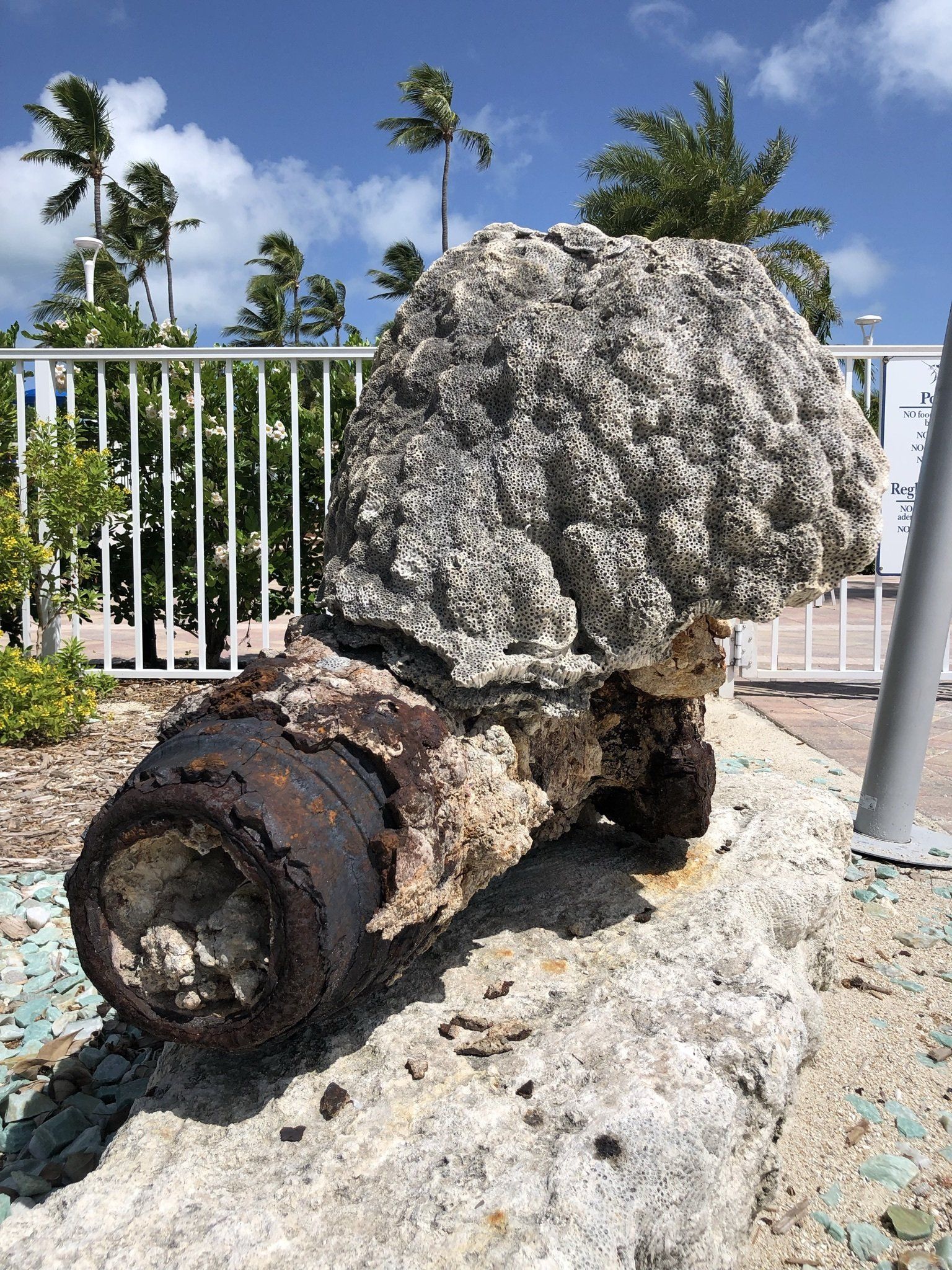 A large rock is sitting on the ground next to a fence.