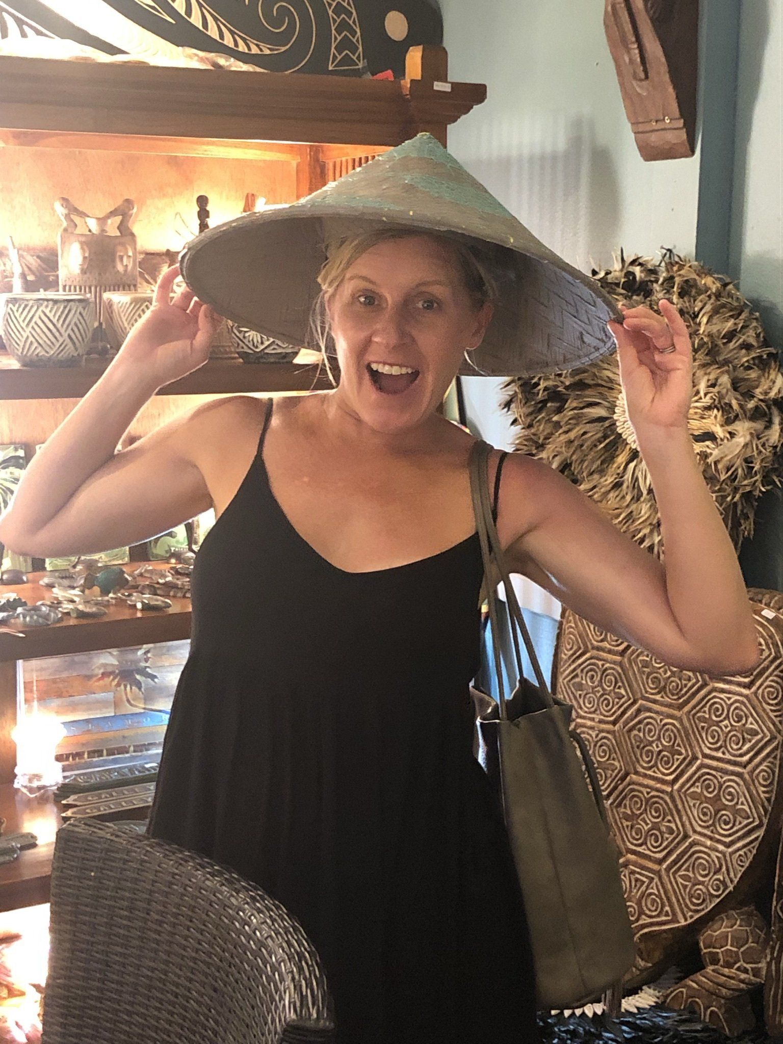 A woman wearing a hat and a black dress is smiling.