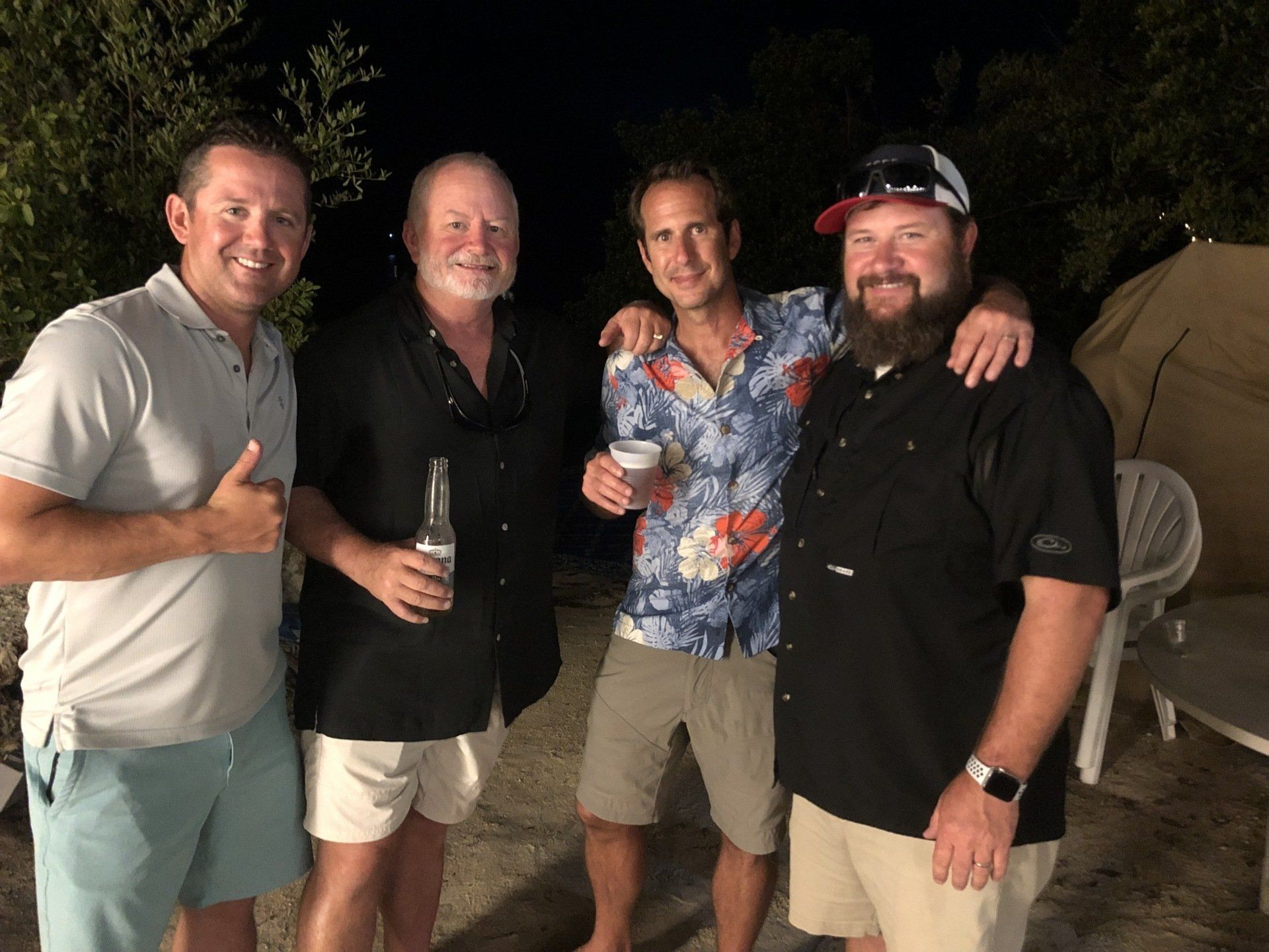 A group of men are posing for a picture and one of them is giving a thumbs up.