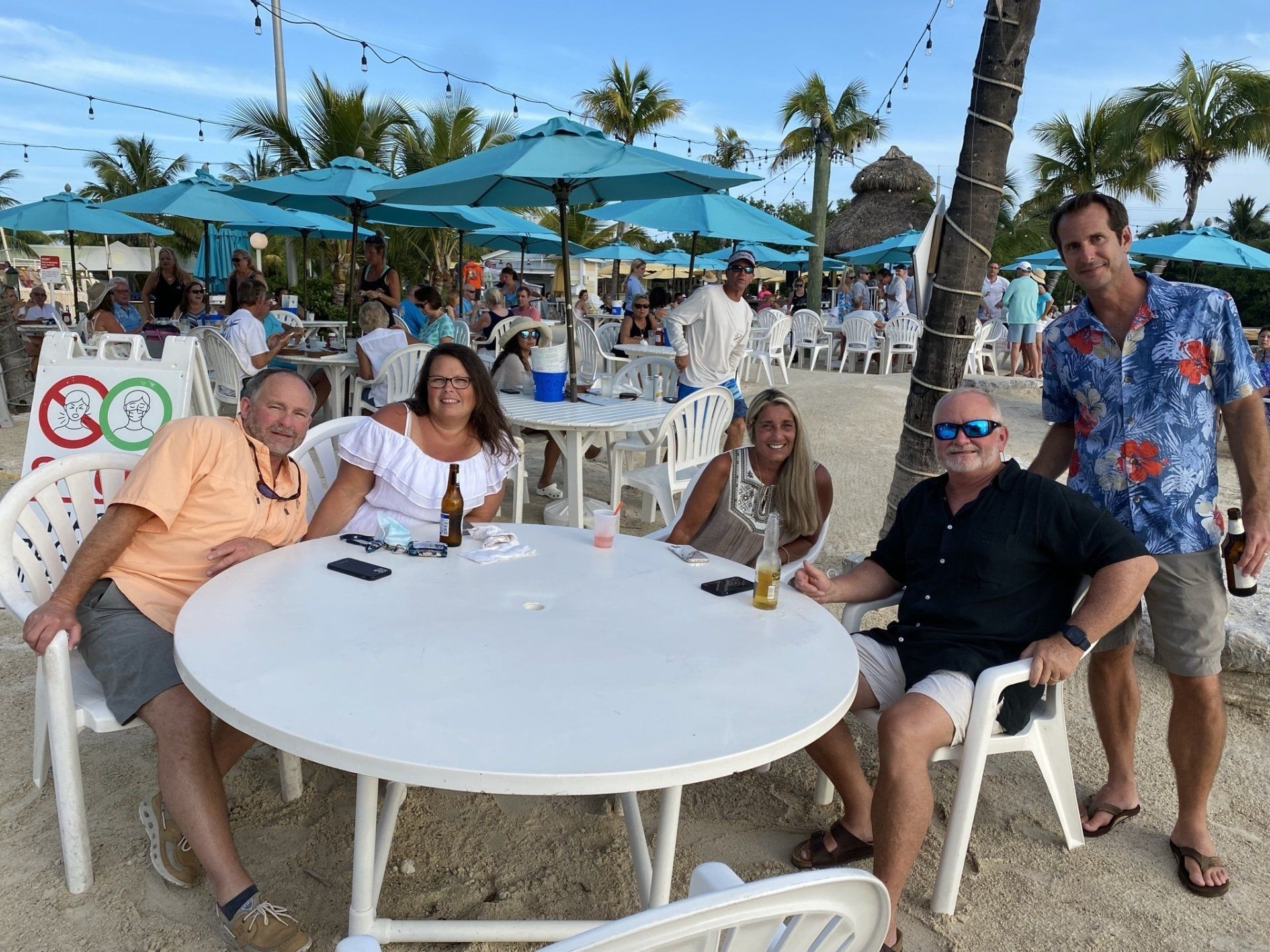 A group of people are sitting at a table on the beach.