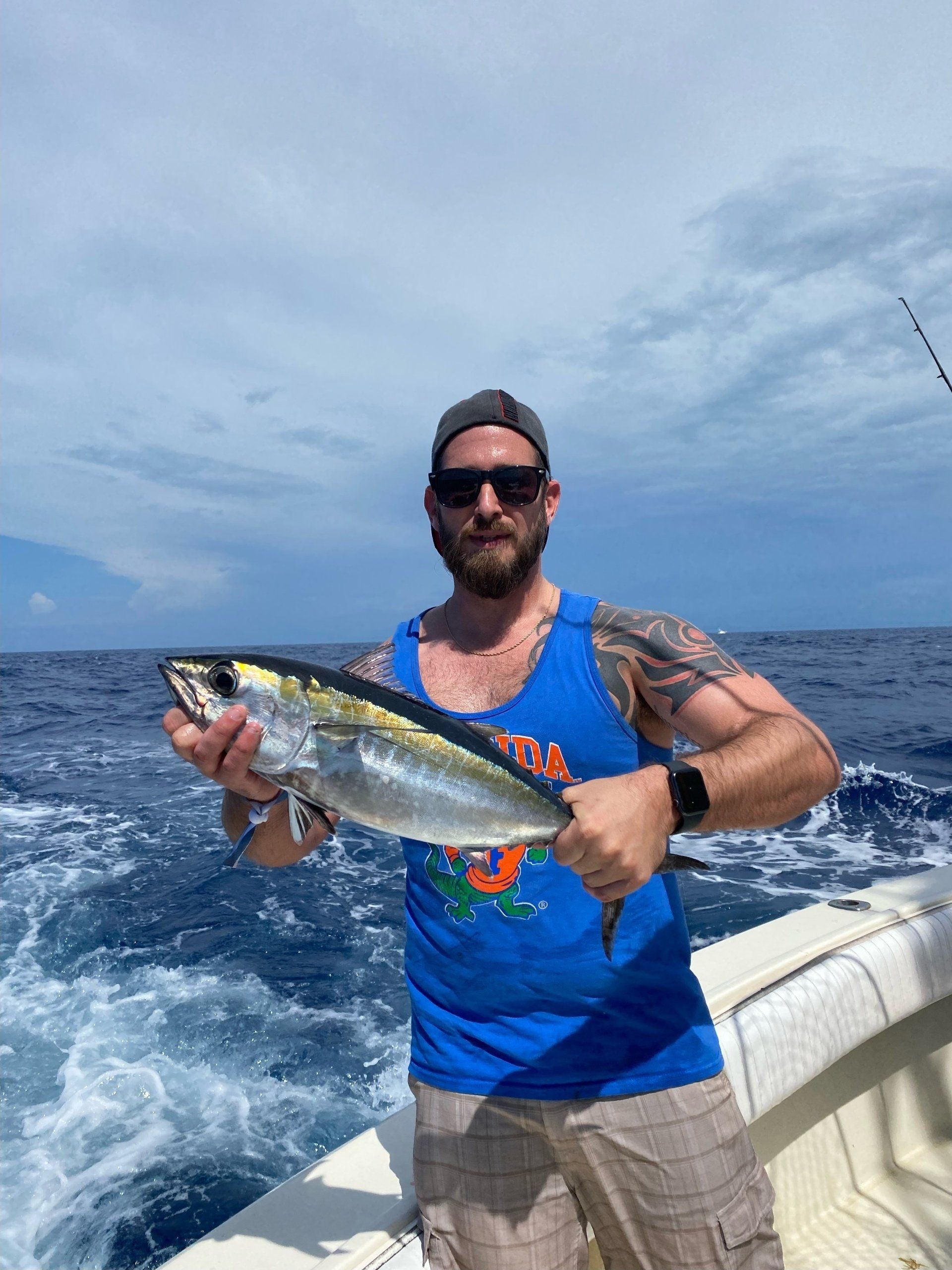 A man is holding a fish on a boat in the ocean.