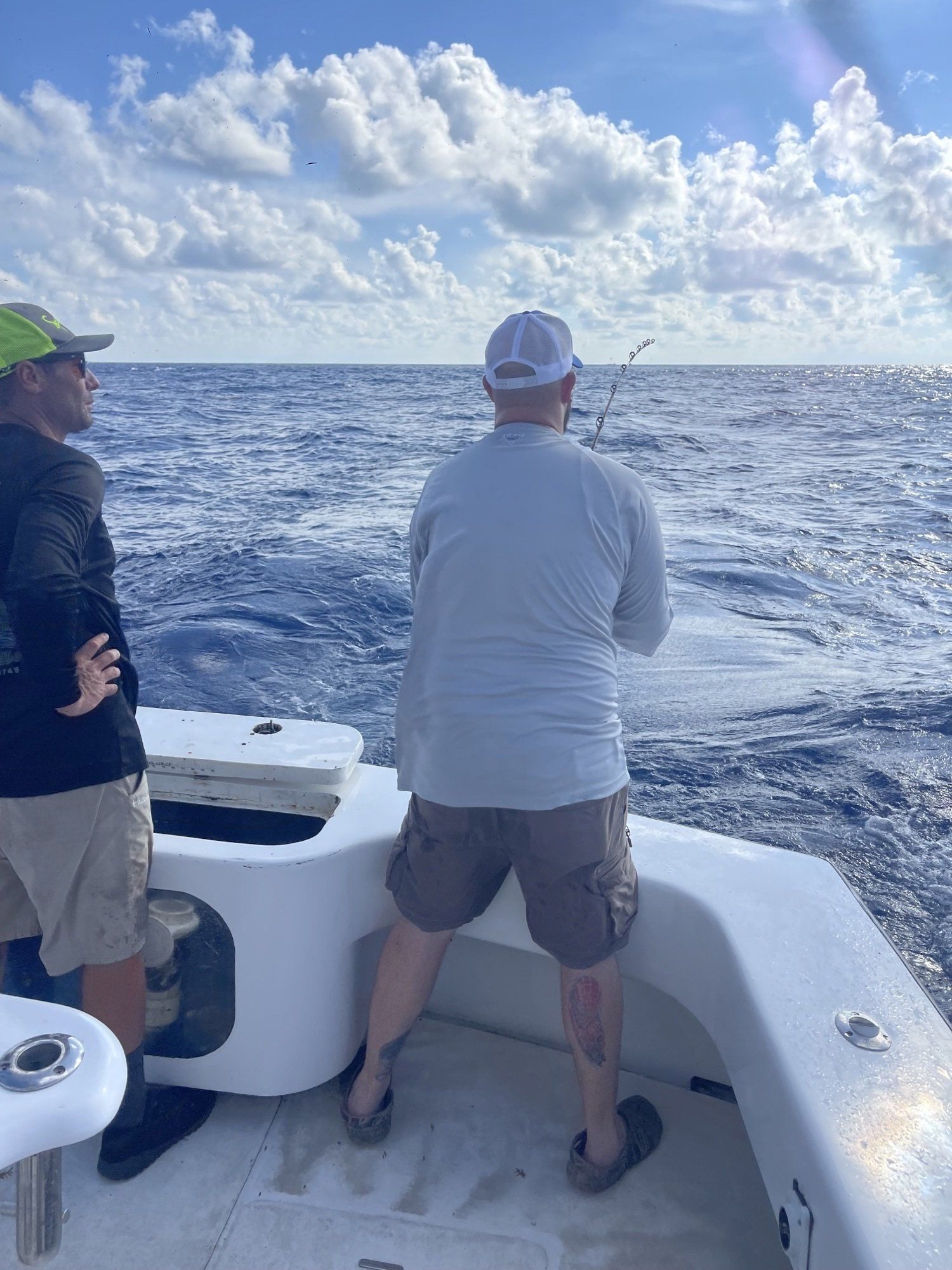 Two men are fishing on a boat in the ocean.