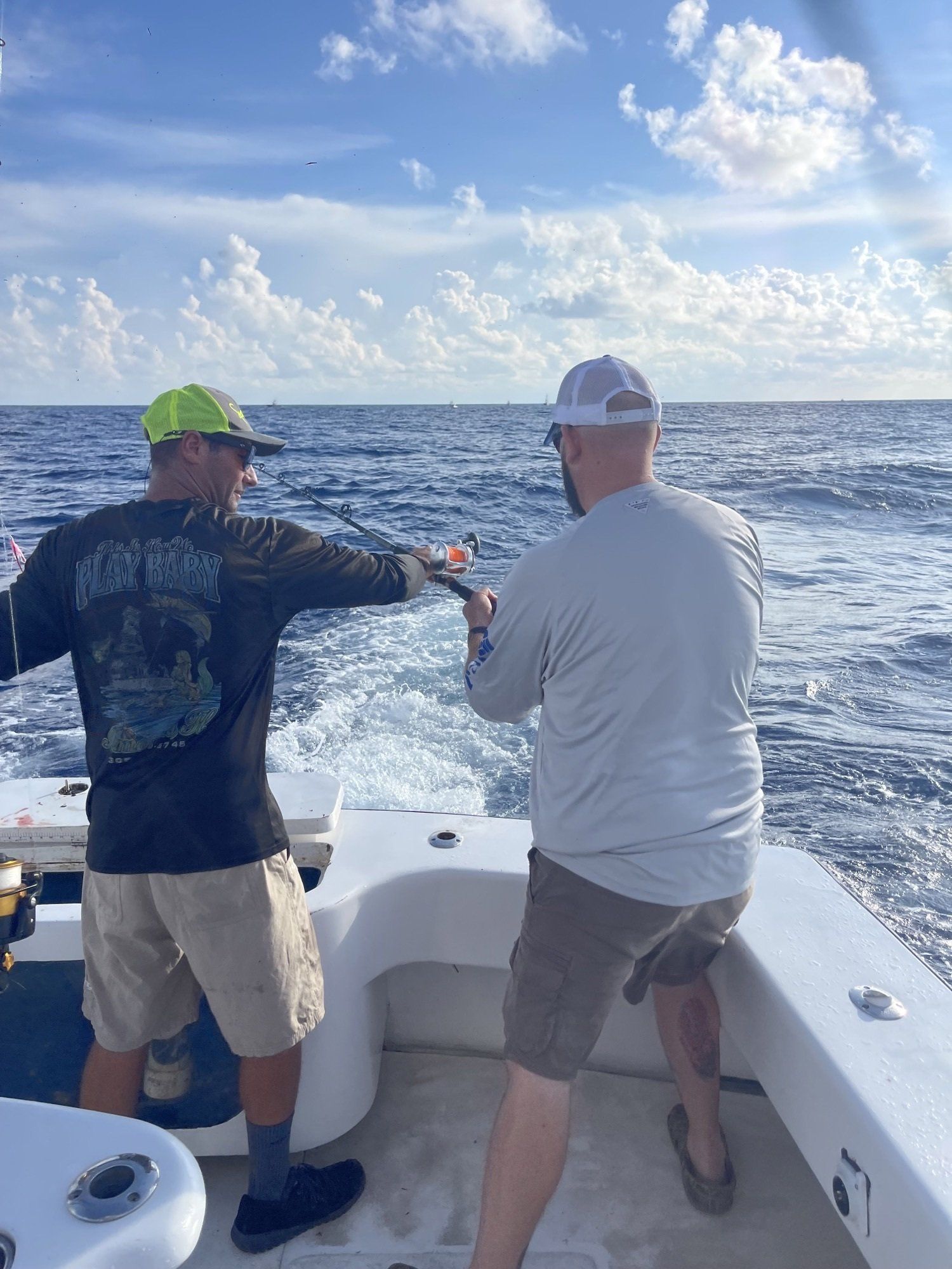 Two men are fishing on a boat in the ocean.