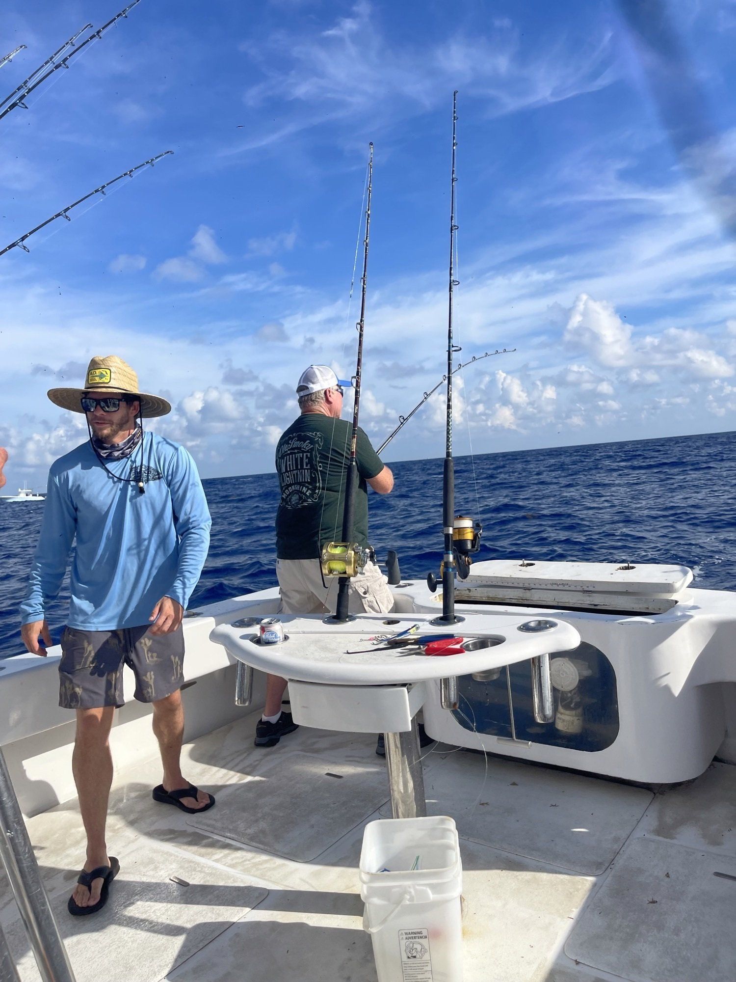 Two men are fishing on a boat in the ocean.