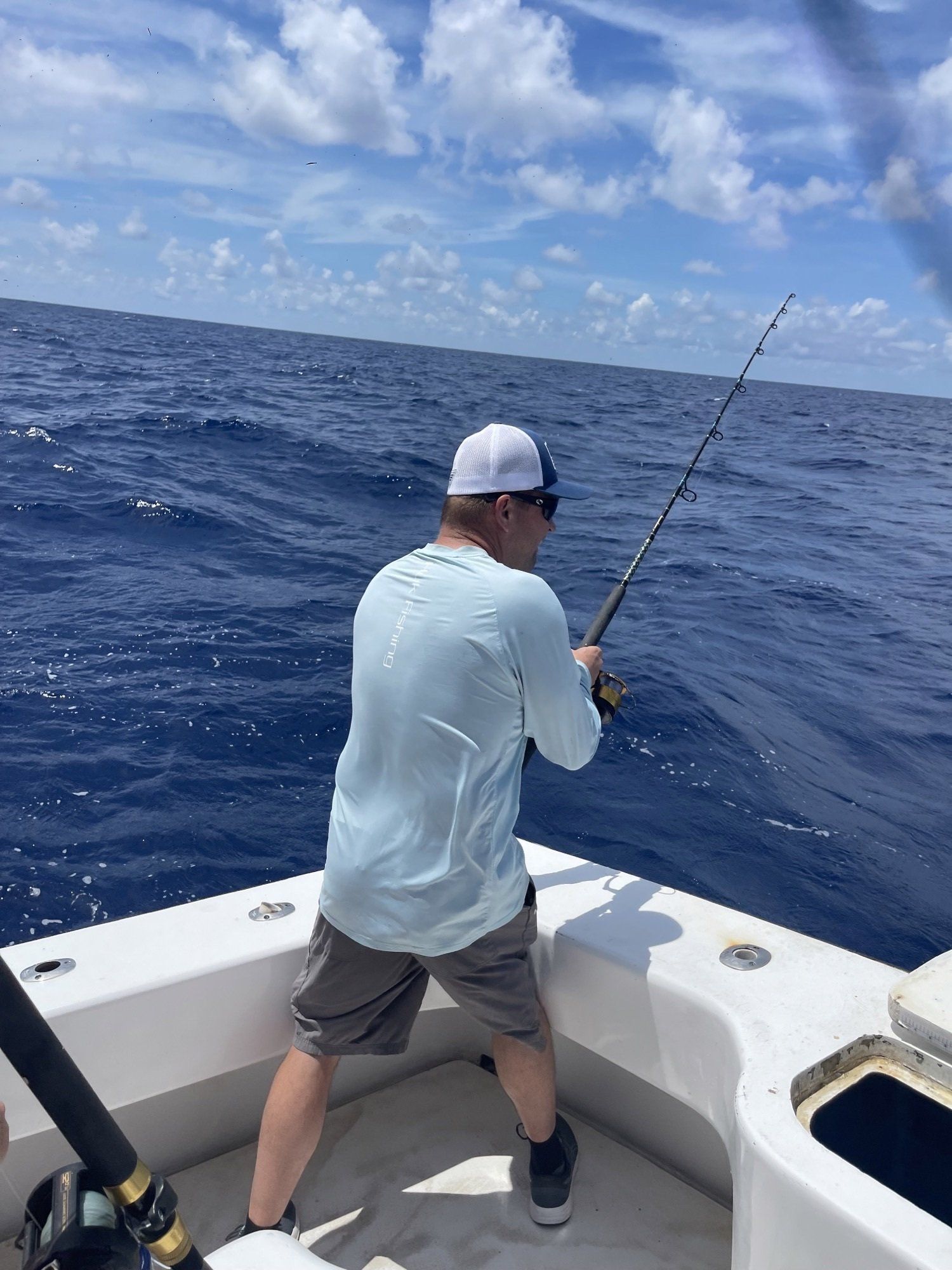 A man is fishing on a boat in the ocean.