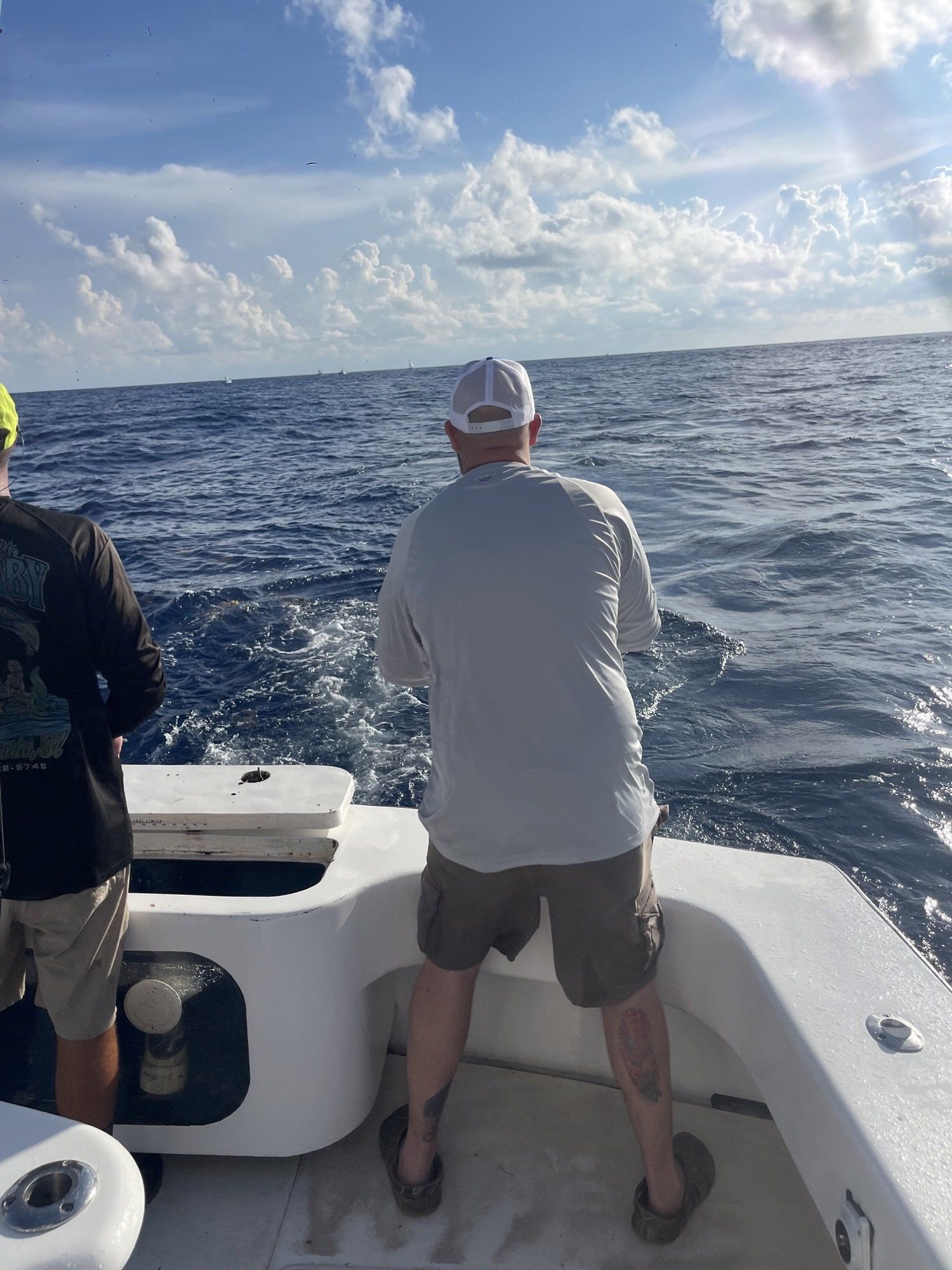 Two men are fishing on a boat in the ocean.