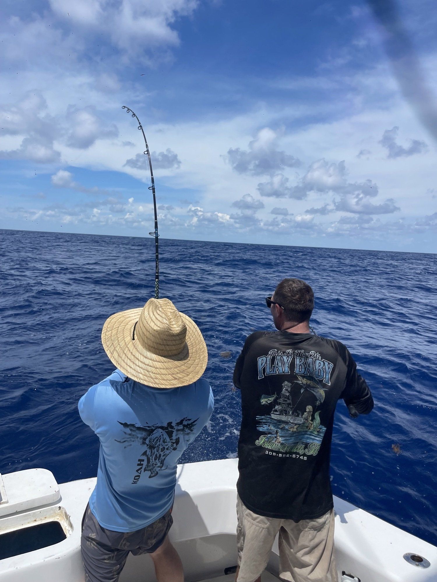 Two men are fishing on a boat in the ocean.