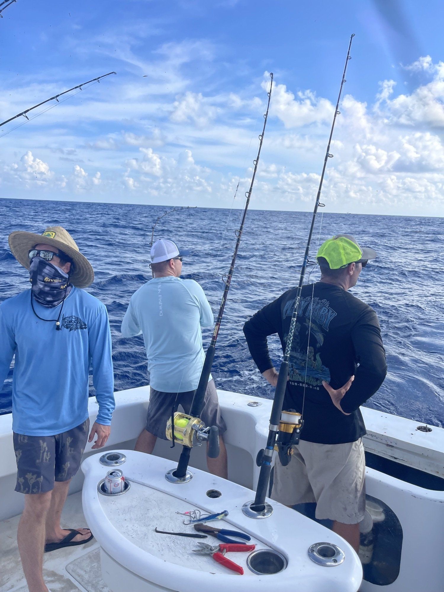 Three men are fishing on a boat in the ocean.