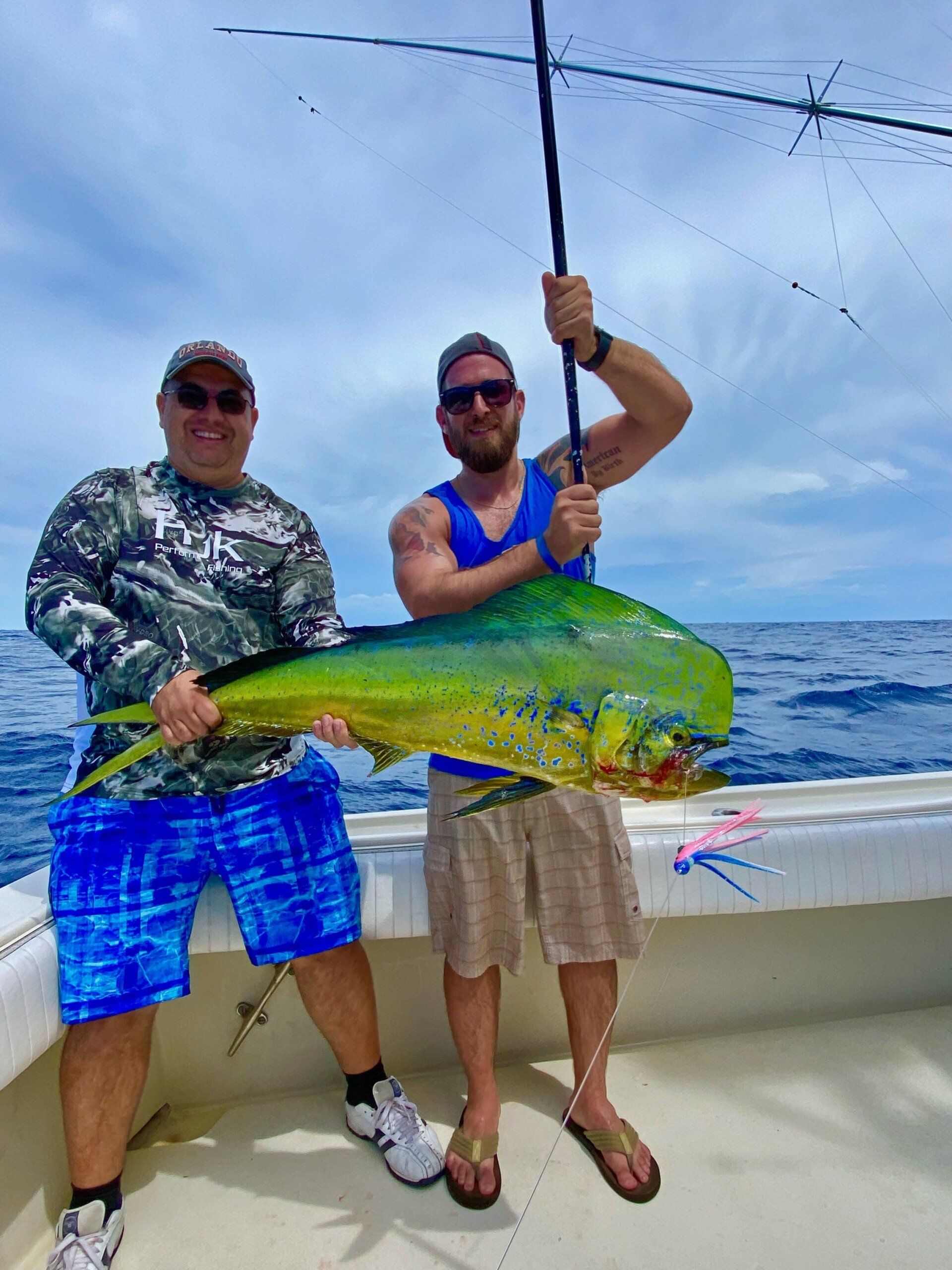 Two men on a boat holding a large fish