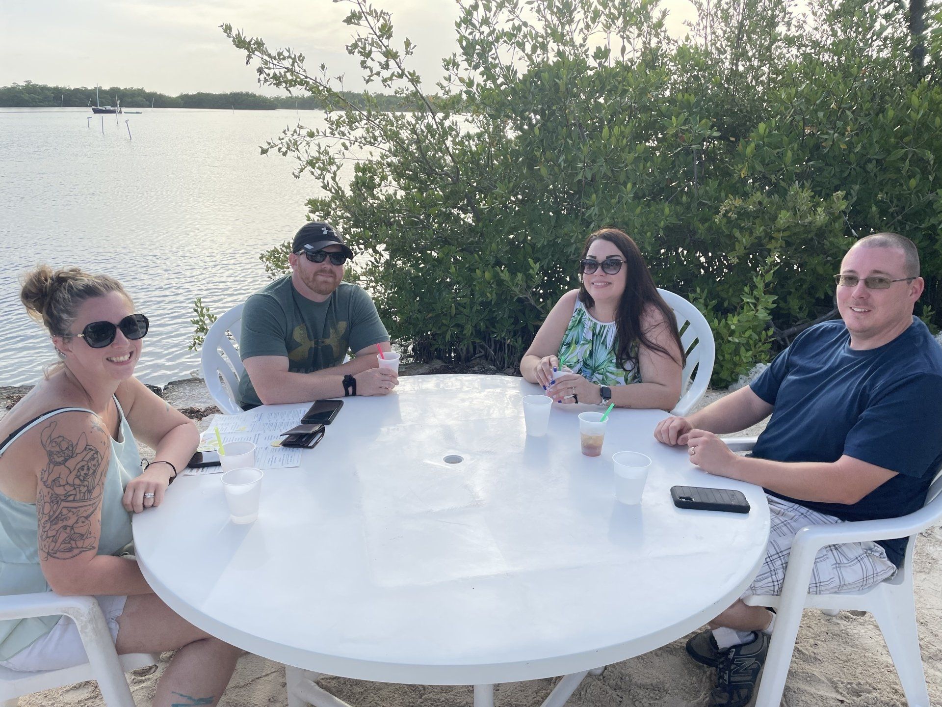 A group of people are sitting at a table by the water.