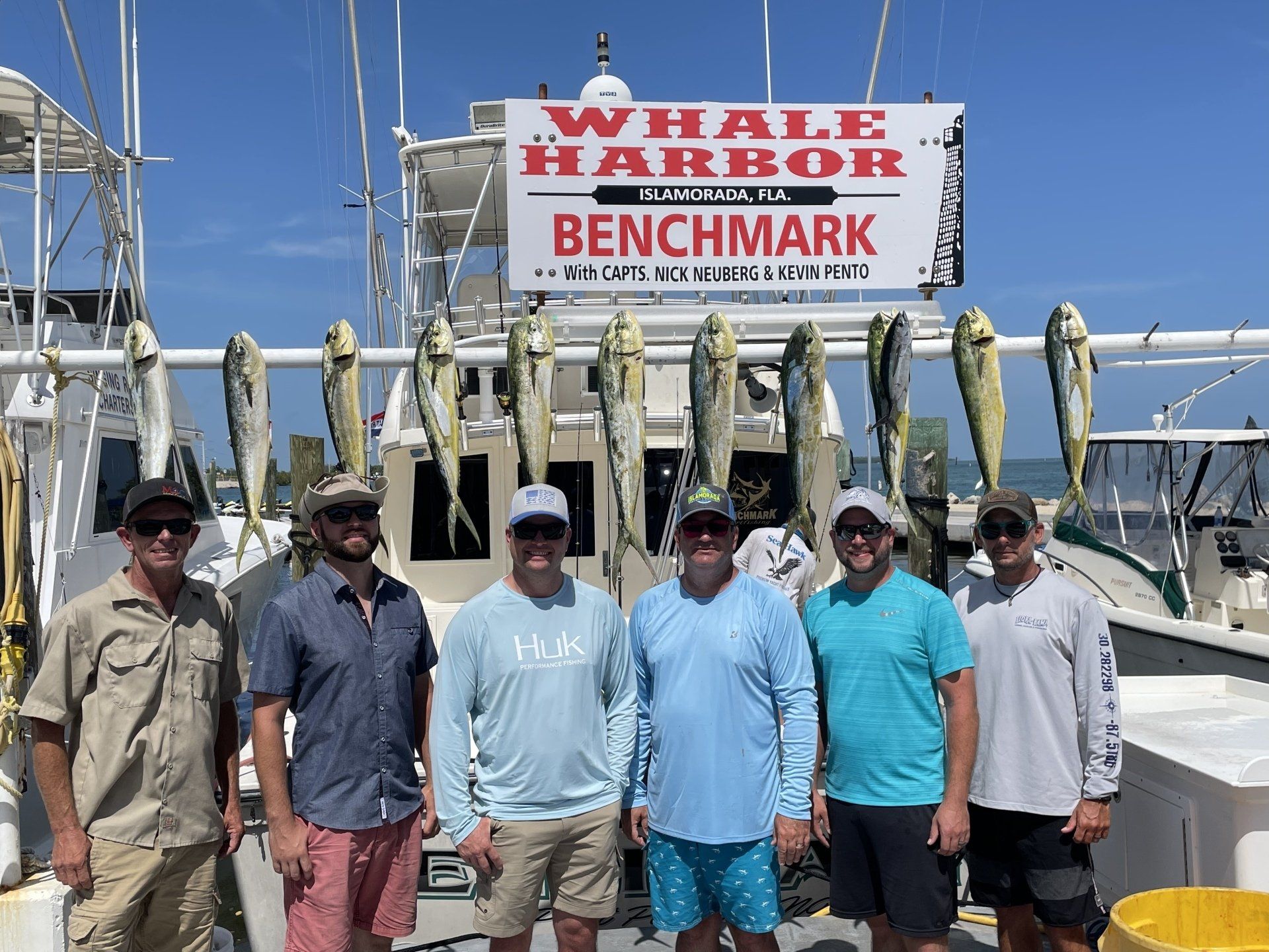 A group of men are standing on a boat with fish on it.