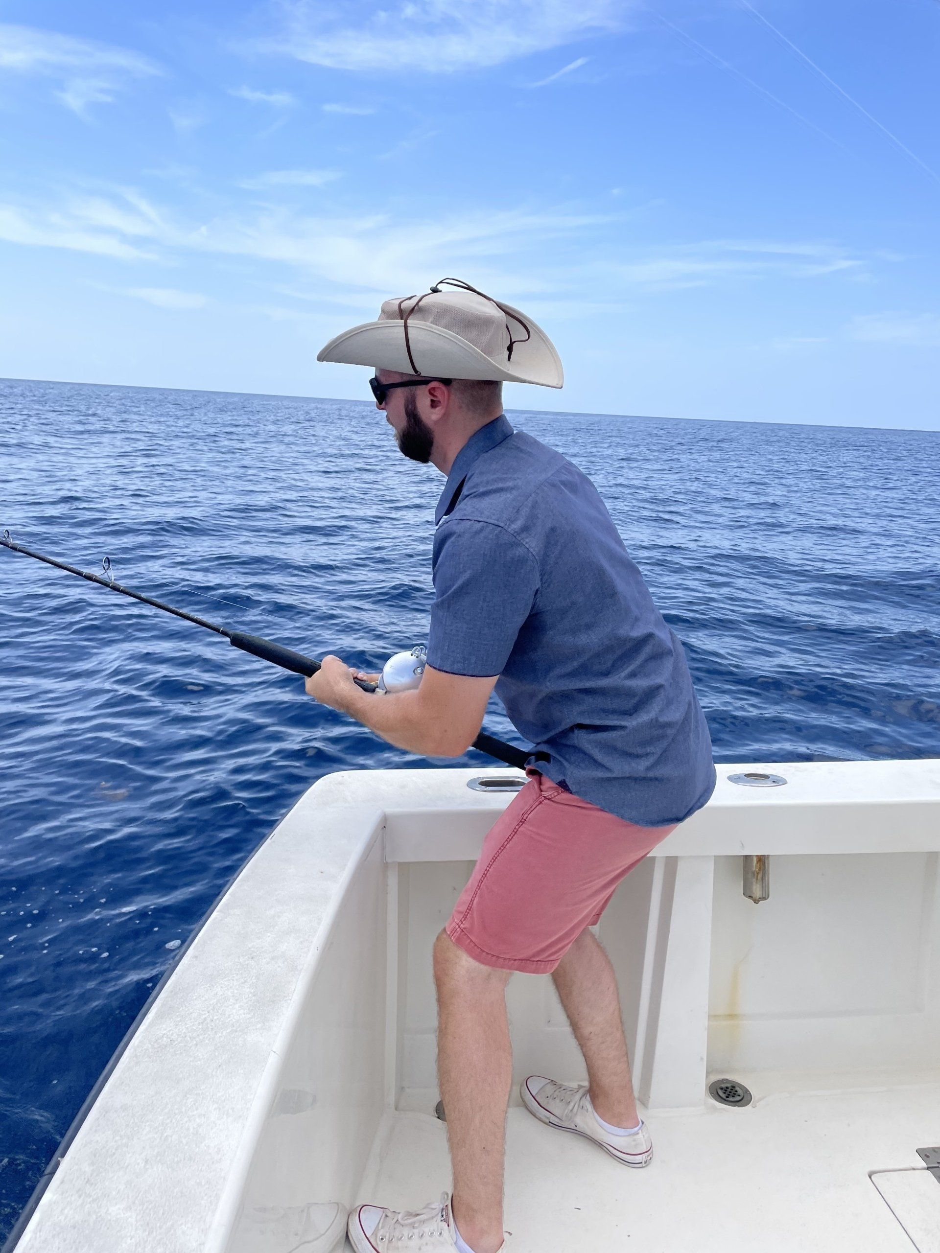 A man in a cowboy hat is fishing on a boat in the ocean.