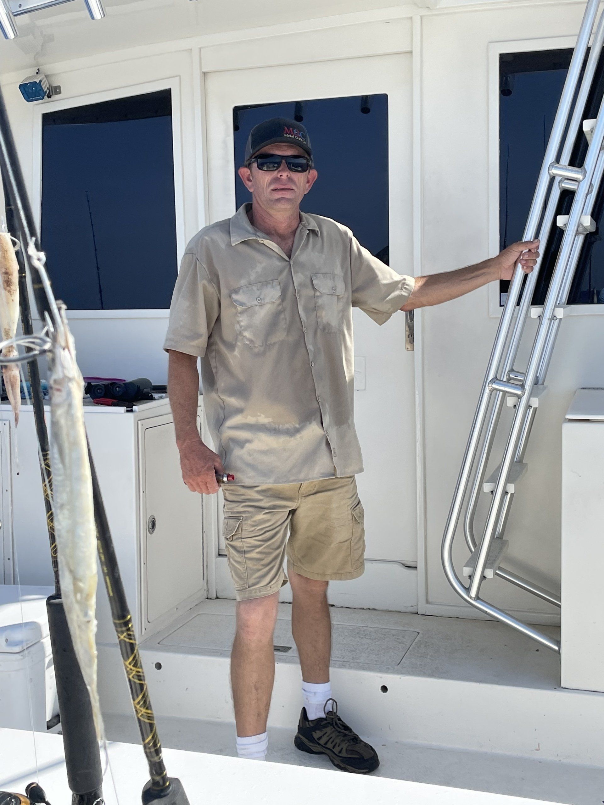 A man is standing on the deck of a boat holding a fishing rod.