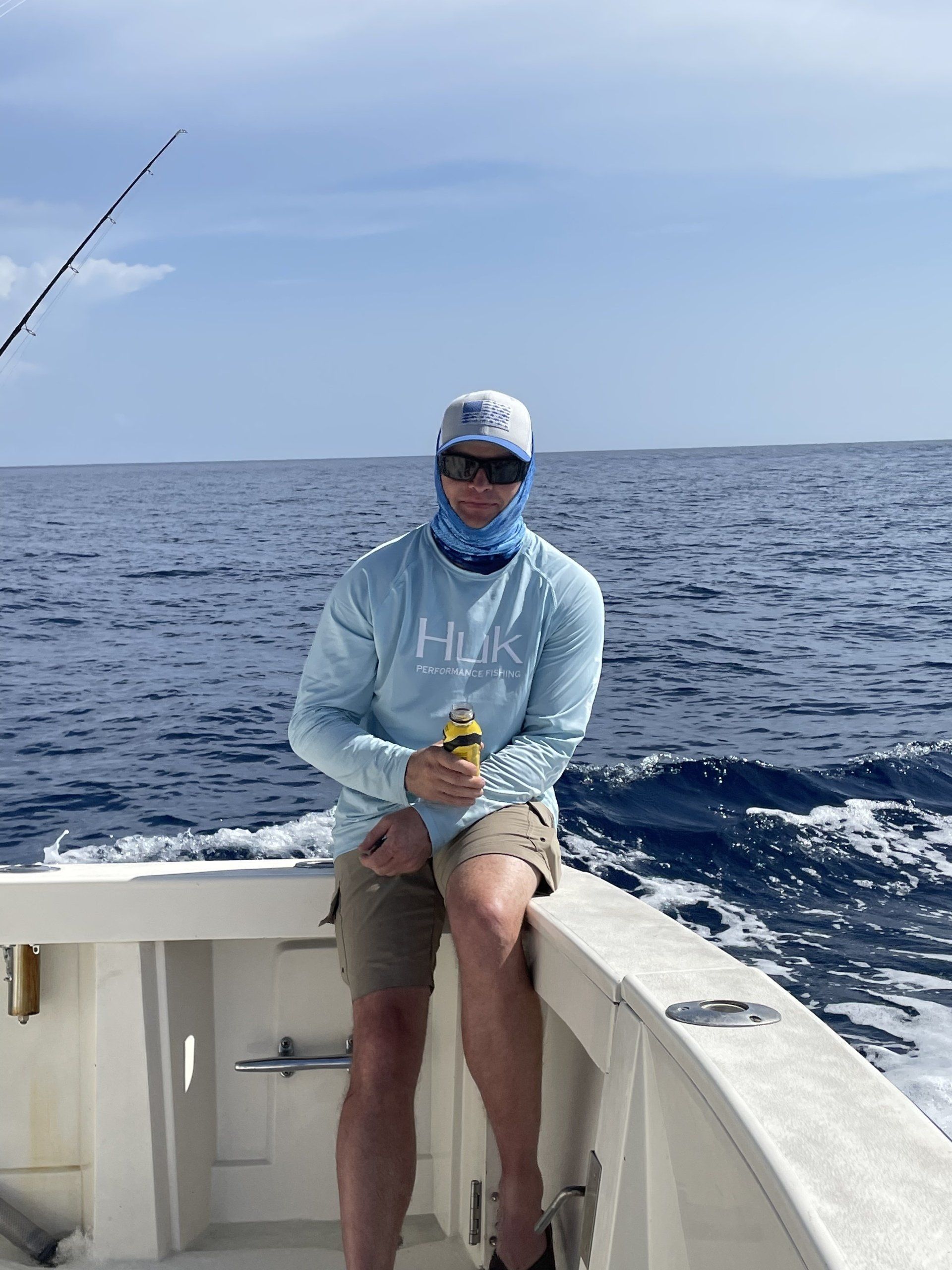 A man is sitting on the side of a boat in the ocean.