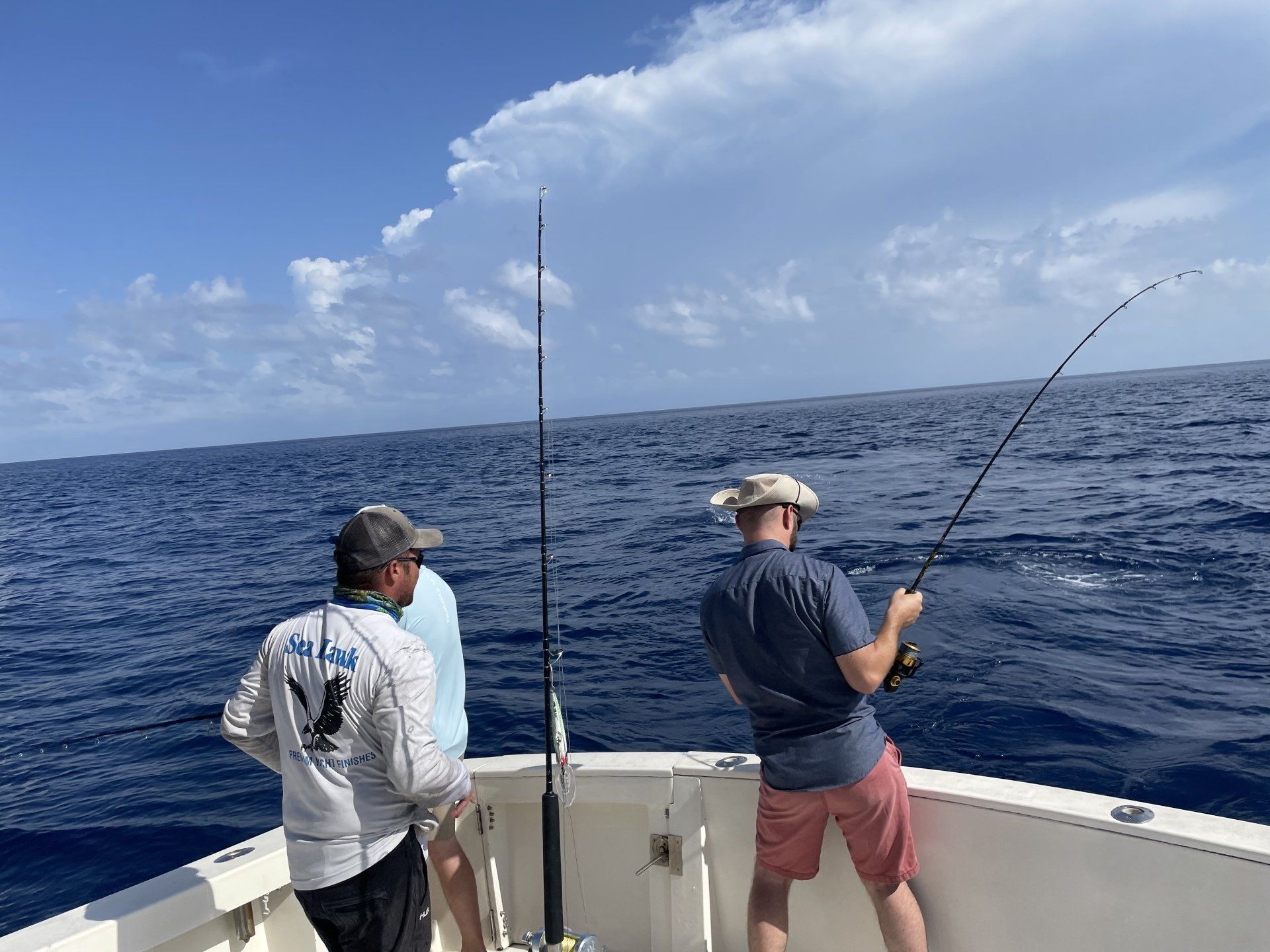 Two men are fishing on a boat in the ocean.