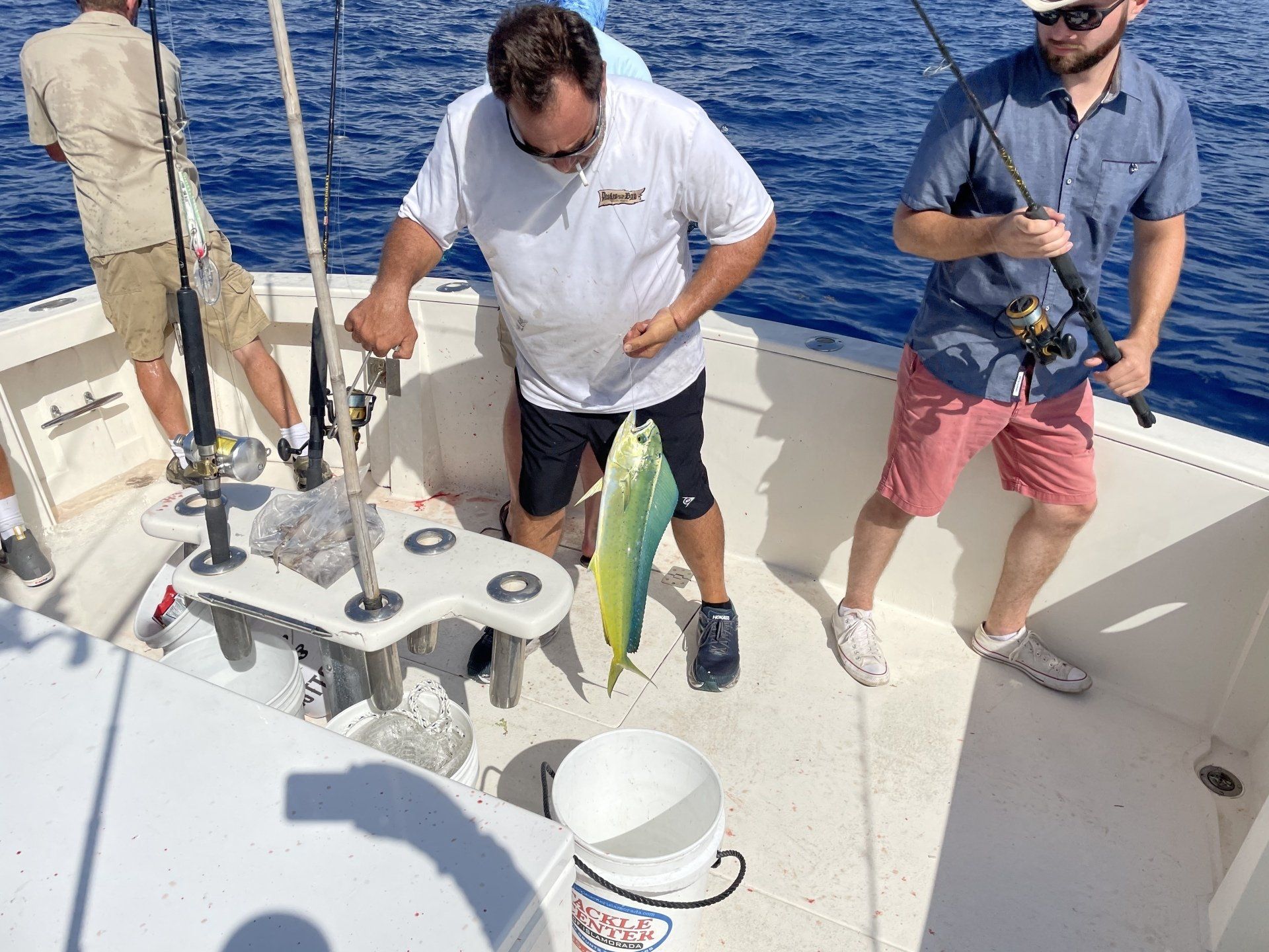 A man is holding a fish on the deck of a boat.