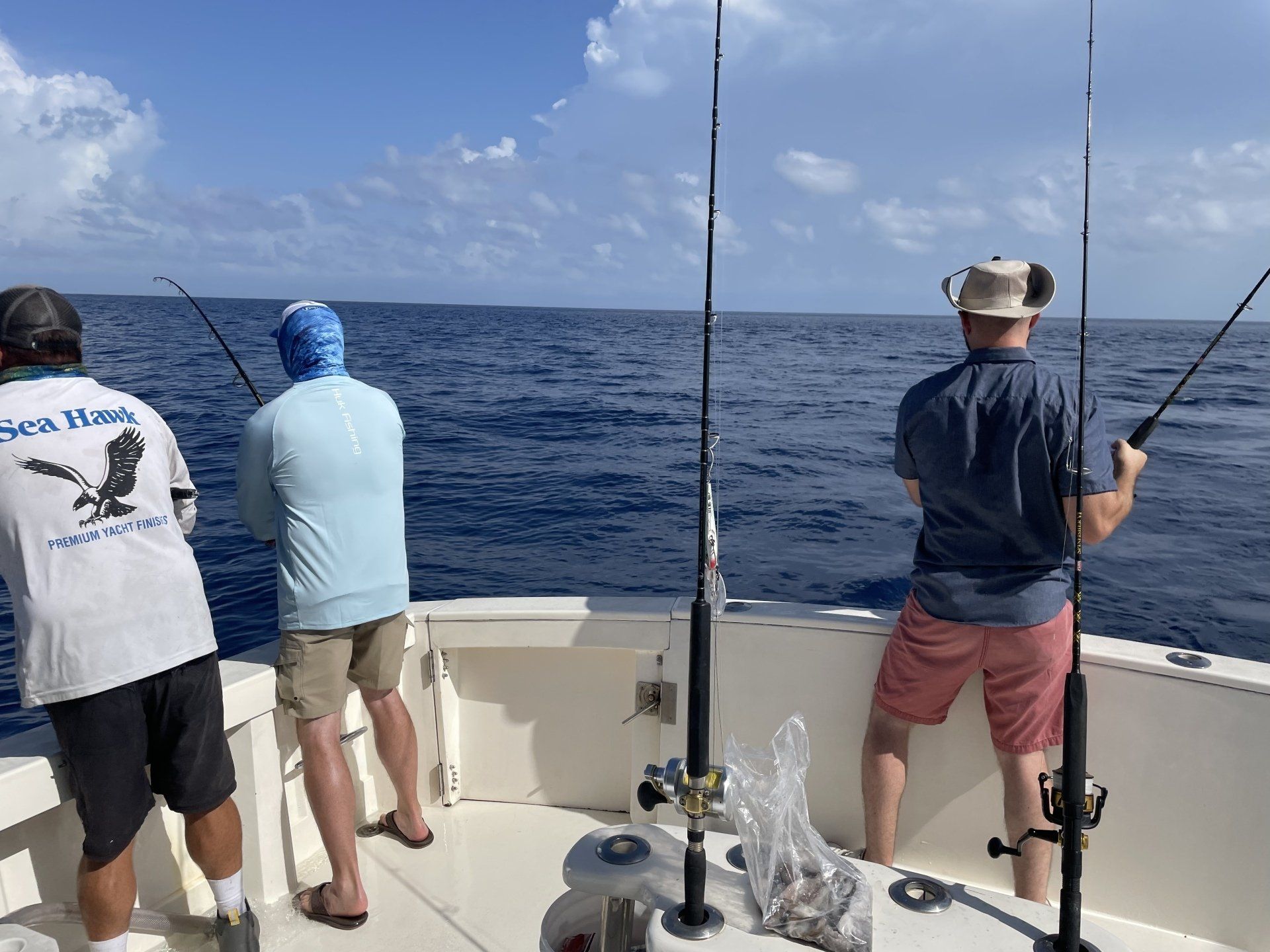 Three men are fishing on a boat in the ocean.