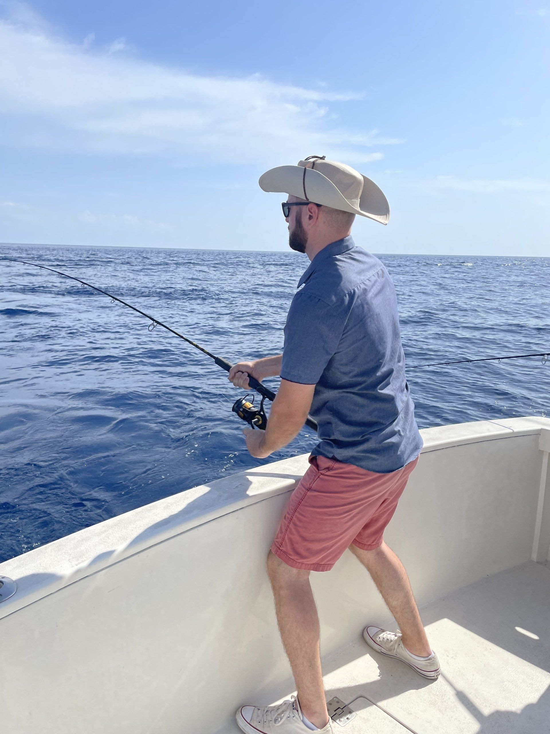A man is fishing on a boat in the ocean.