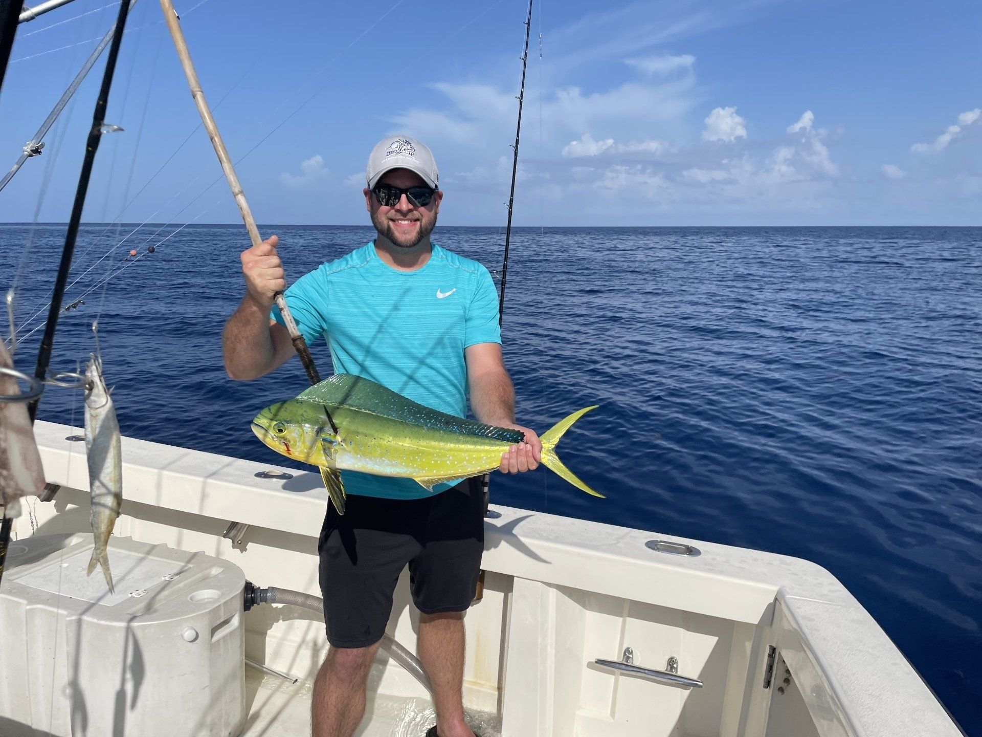 A man is holding a fish on a boat in the ocean.