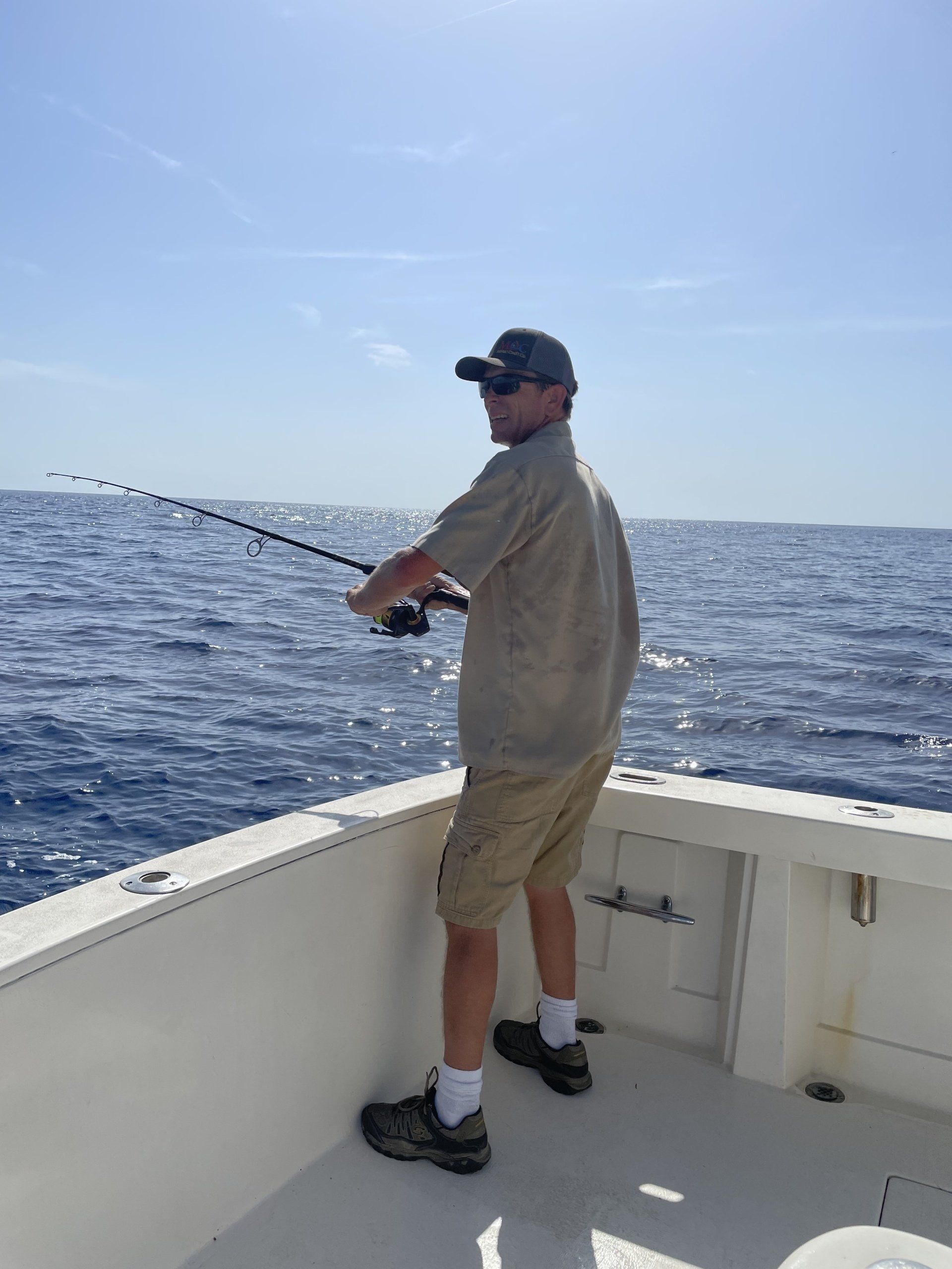 A man is fishing on a boat in the ocean.