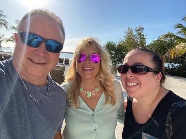 A man and two women wearing sunglasses are posing for a picture.