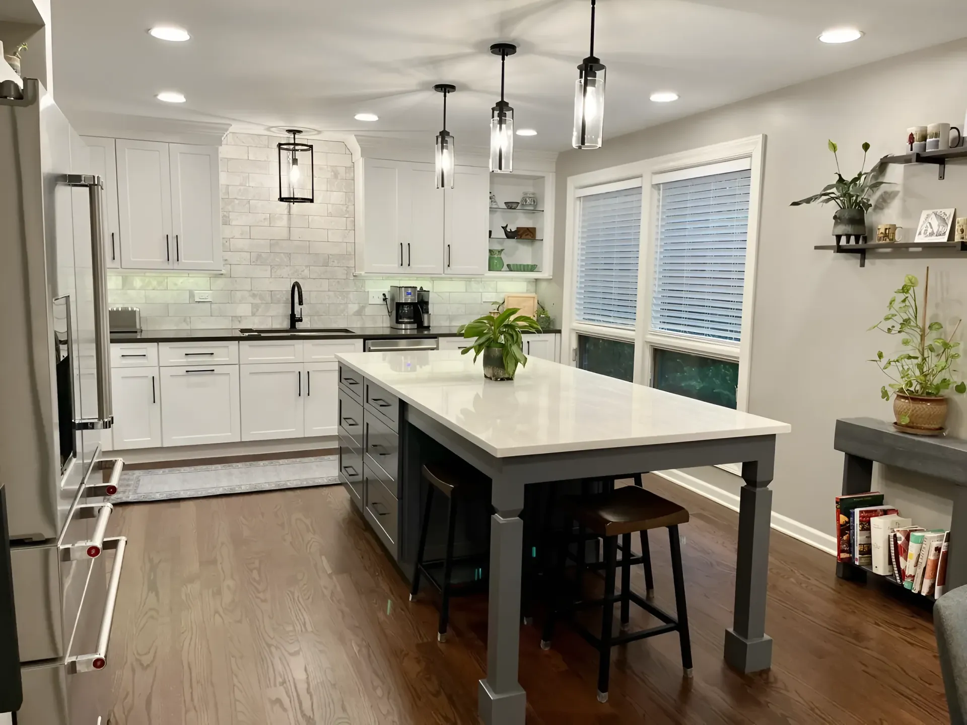 Bright modern kitchen with white cabinets, large island, pendant lights, and sliding glass doors