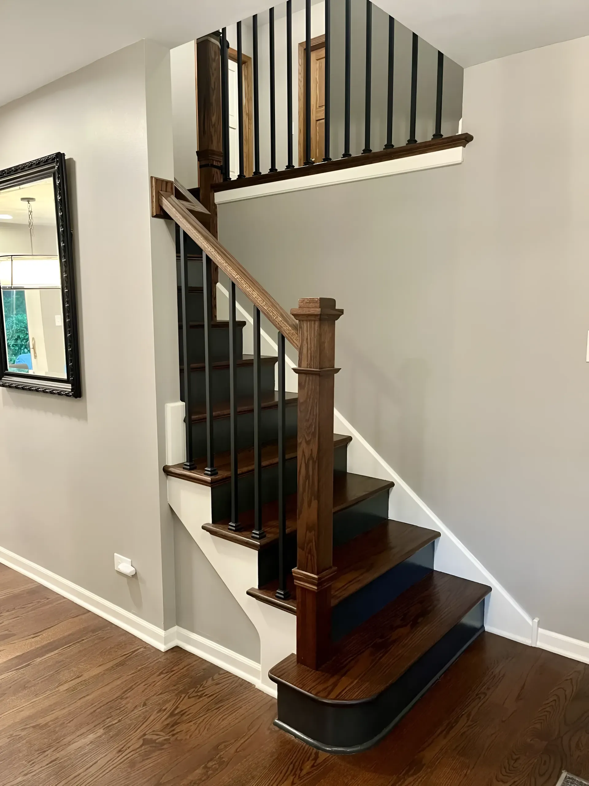 Curved wooden staircase with dark steps and white walls in a home interior